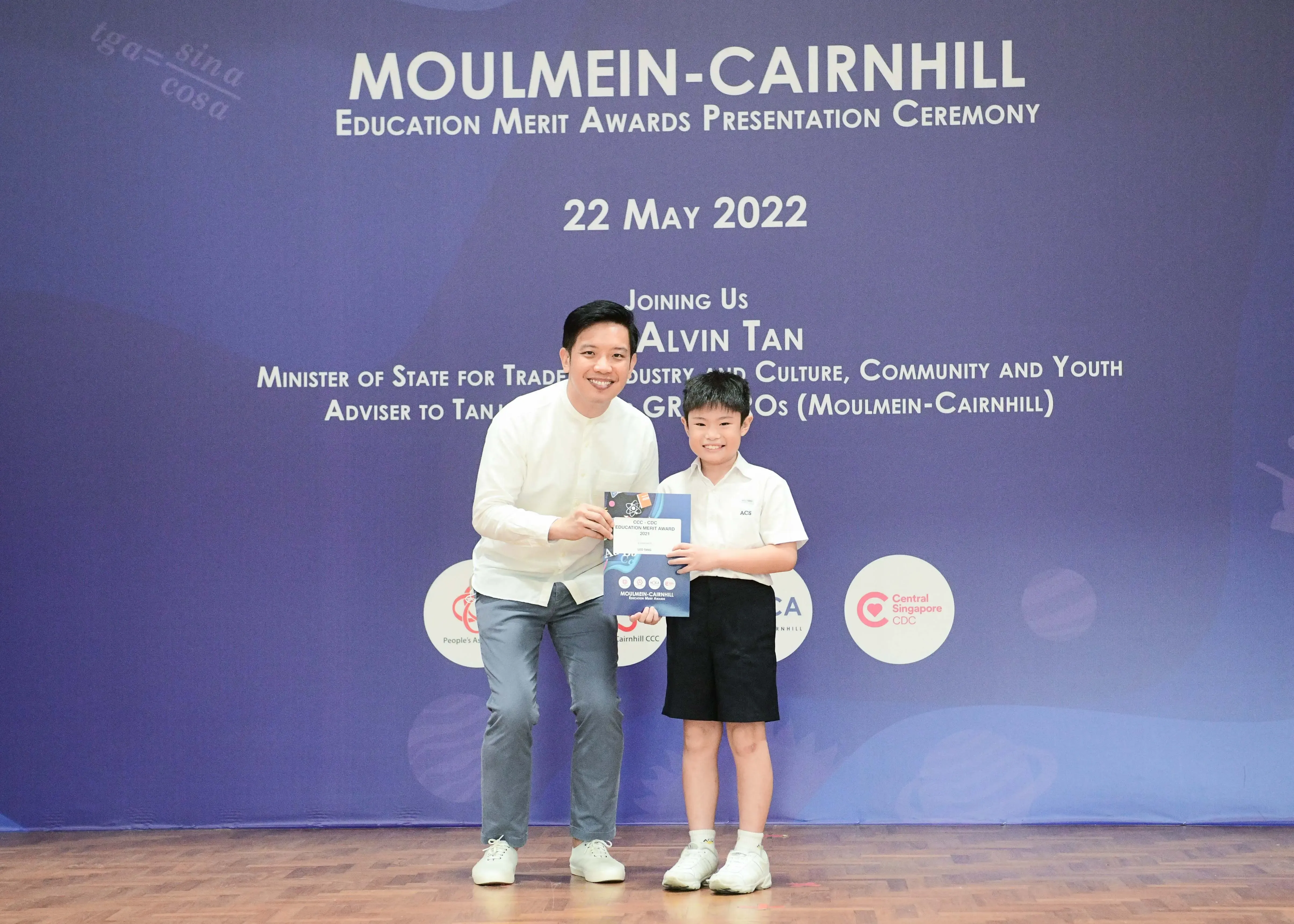A man and a young boy hold an award certificate at the Moulmein-Cairnhill Education Merit Awards on 22 May 2022.