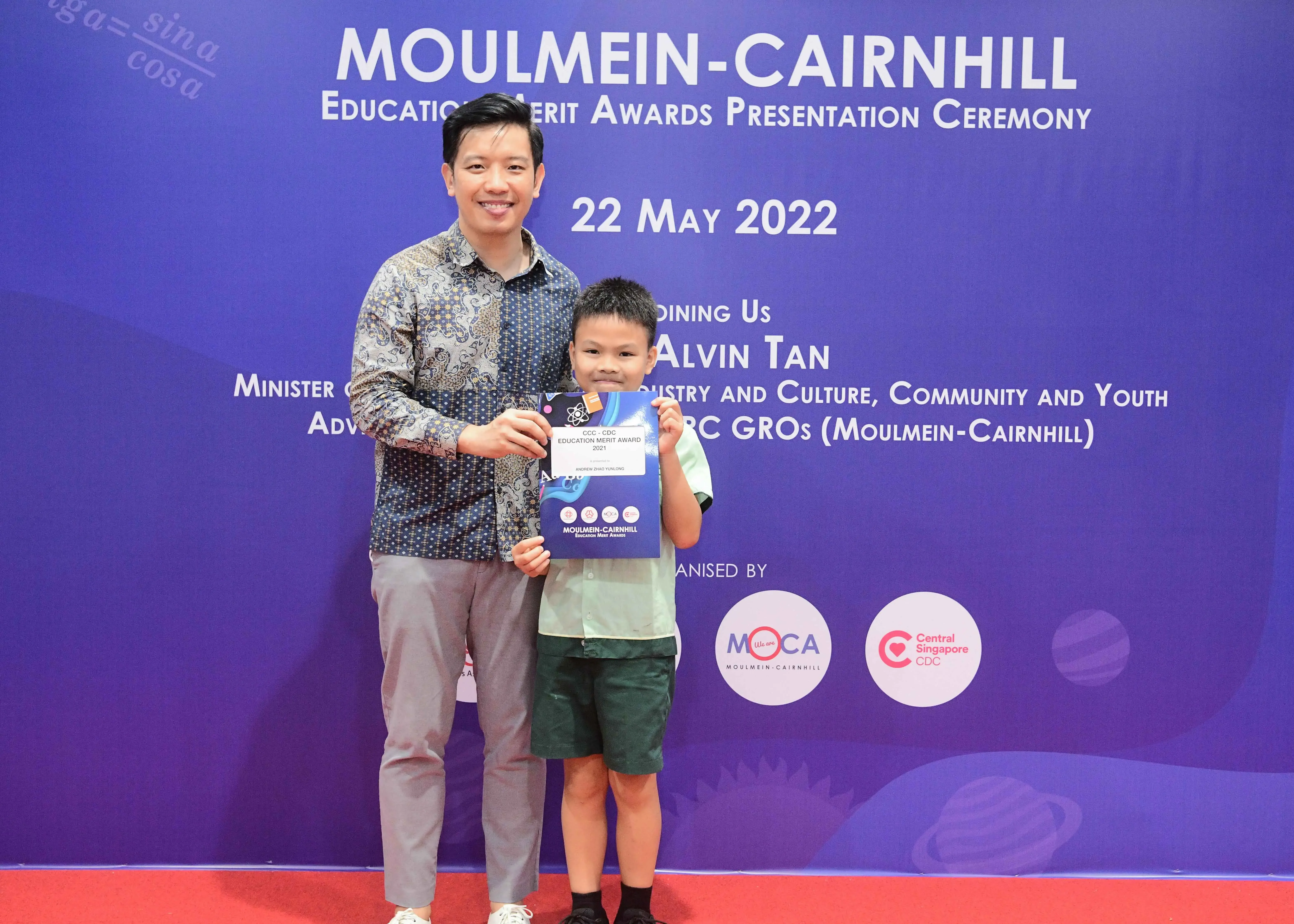 Man and young boy pose holding an award certificate at the Moulmein-Cairnhill Education Merit Awards on 22 May 2022.