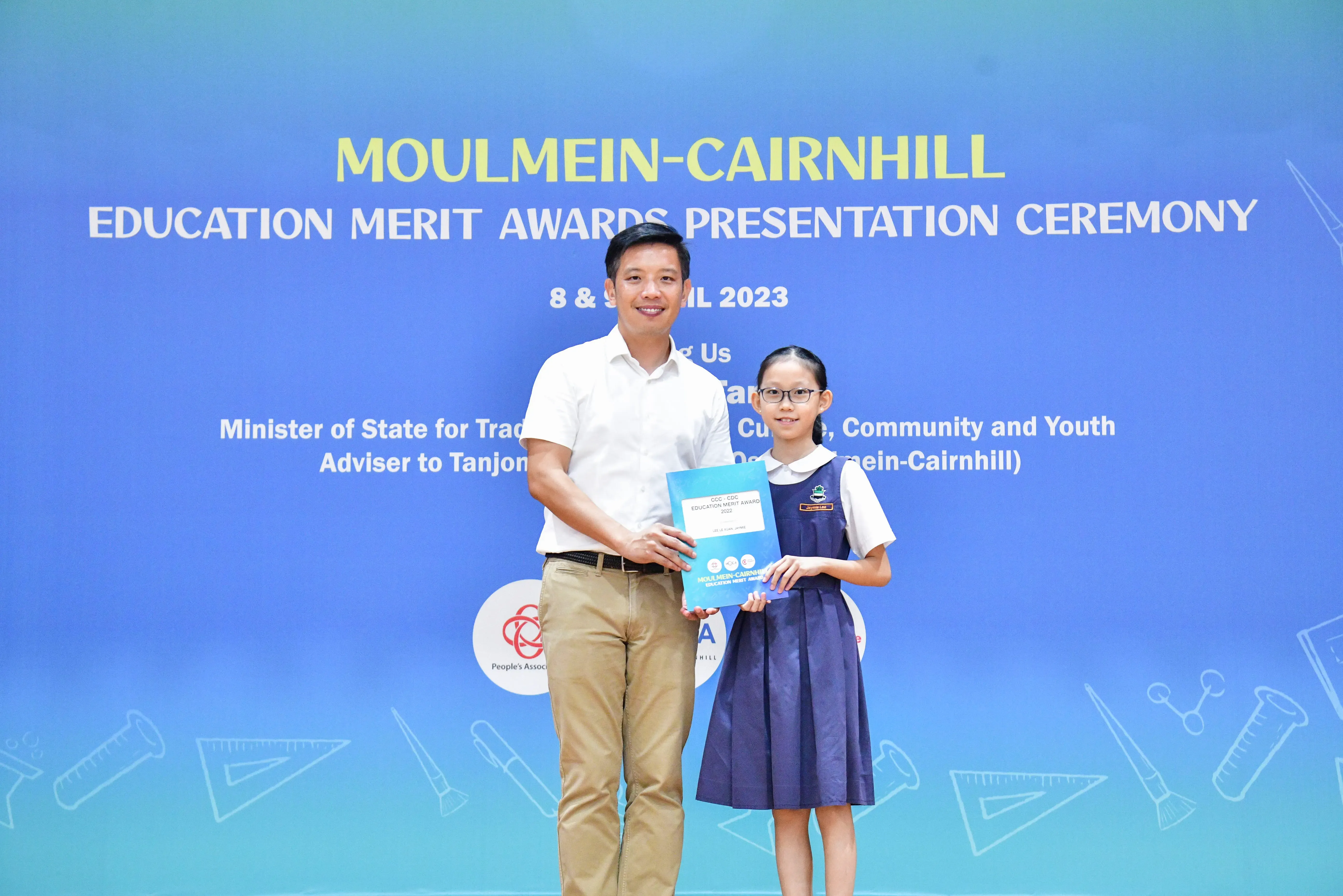 A man and a young girl in school uniform hold a certificate at the Moulmein-Cairnhill Education Merit Awards 2023.