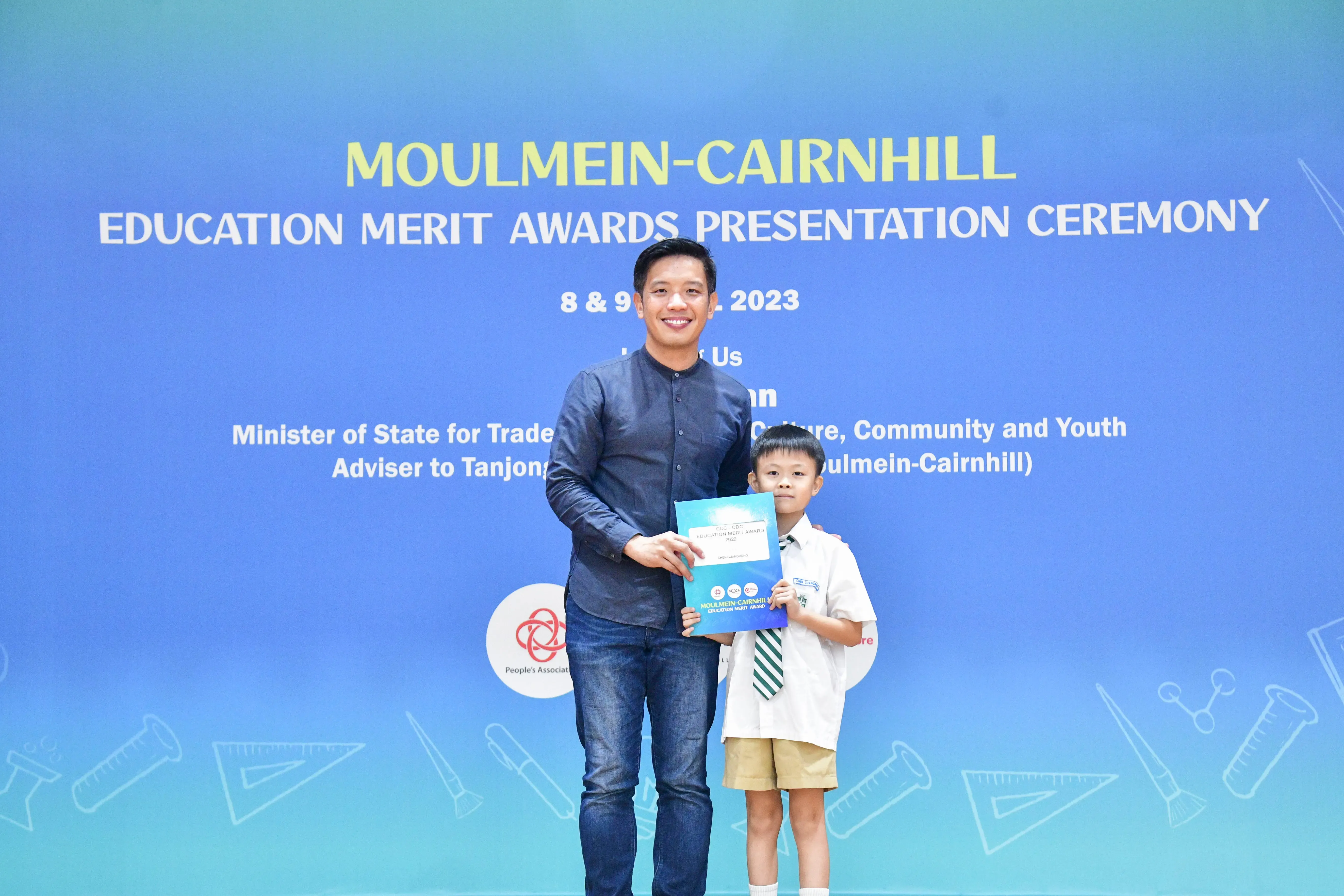 A man and a young boy in school uniform hold a certificate at the Moulmein-Cairnhill Education Merit Awards 2023.