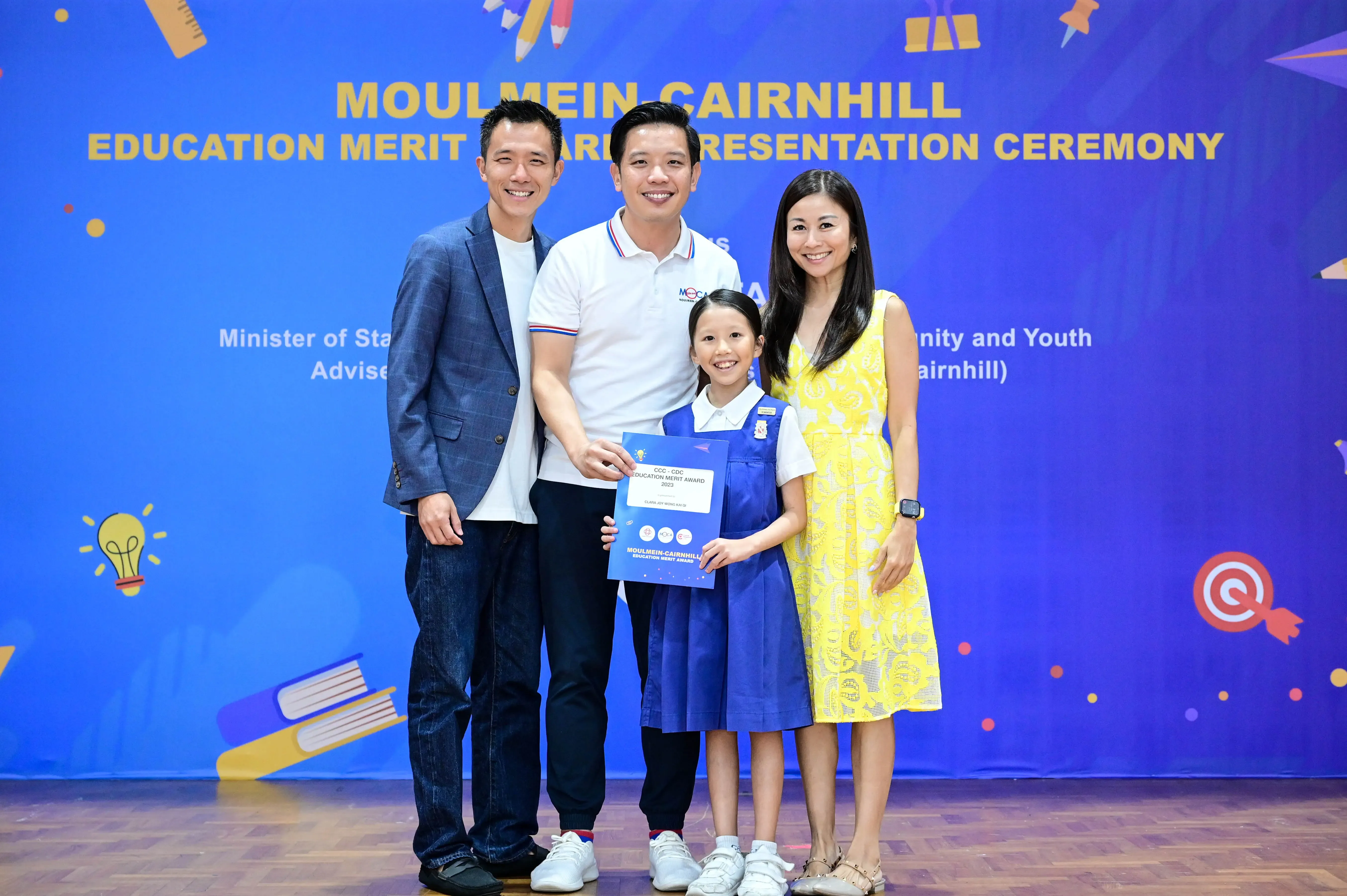 Three adults and a young girl holding a certificate pose at the Moulmein-Cairnhill Education Merit Award ceremony.