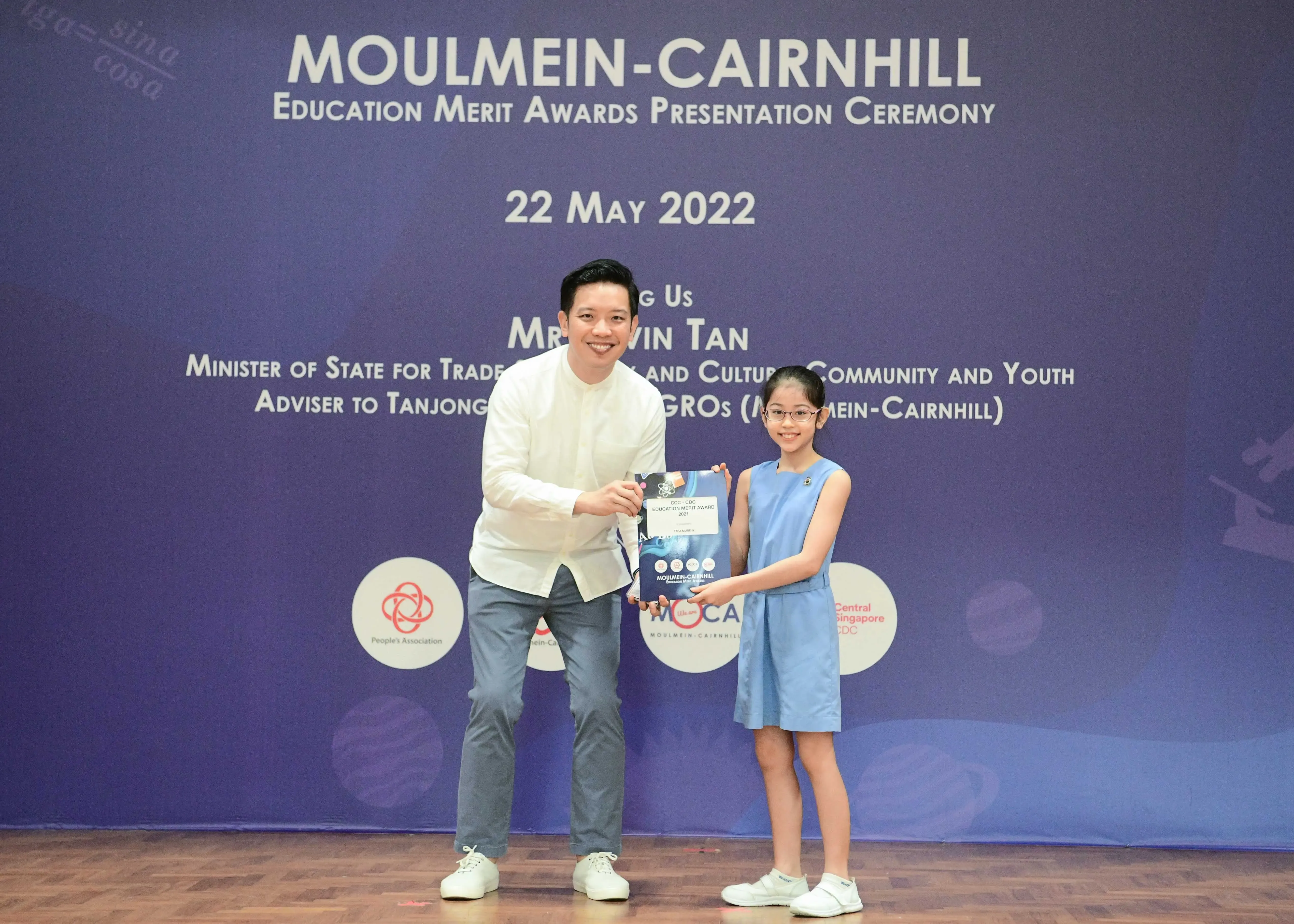 A man and a young girl hold a certificate together at the Moulmein-Cairnhill Education Merit Awards on 22 May 2022.