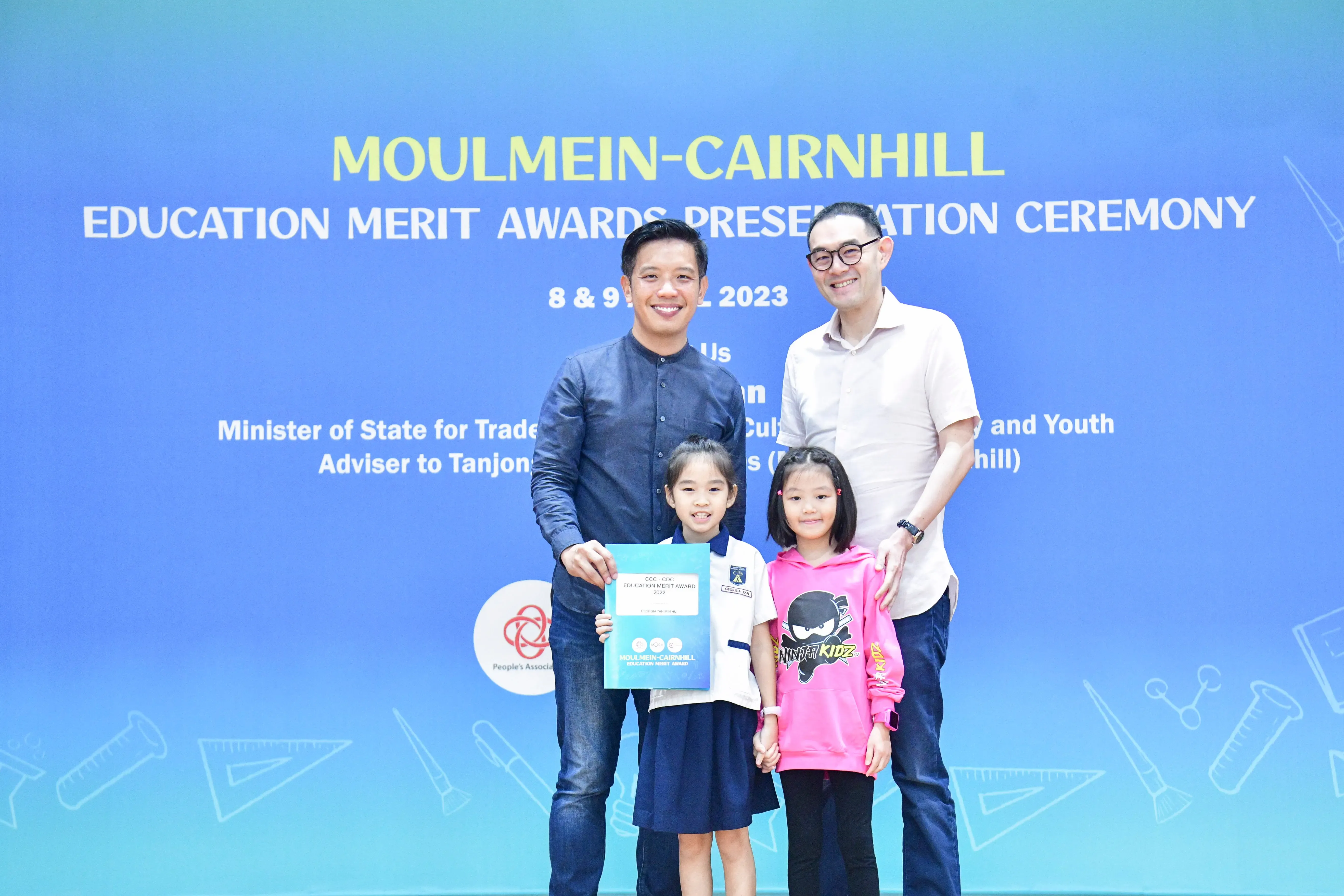 Two men and two young girls pose at the Moulmein-Cairnhill Education Merit Awards Ceremony 2023.