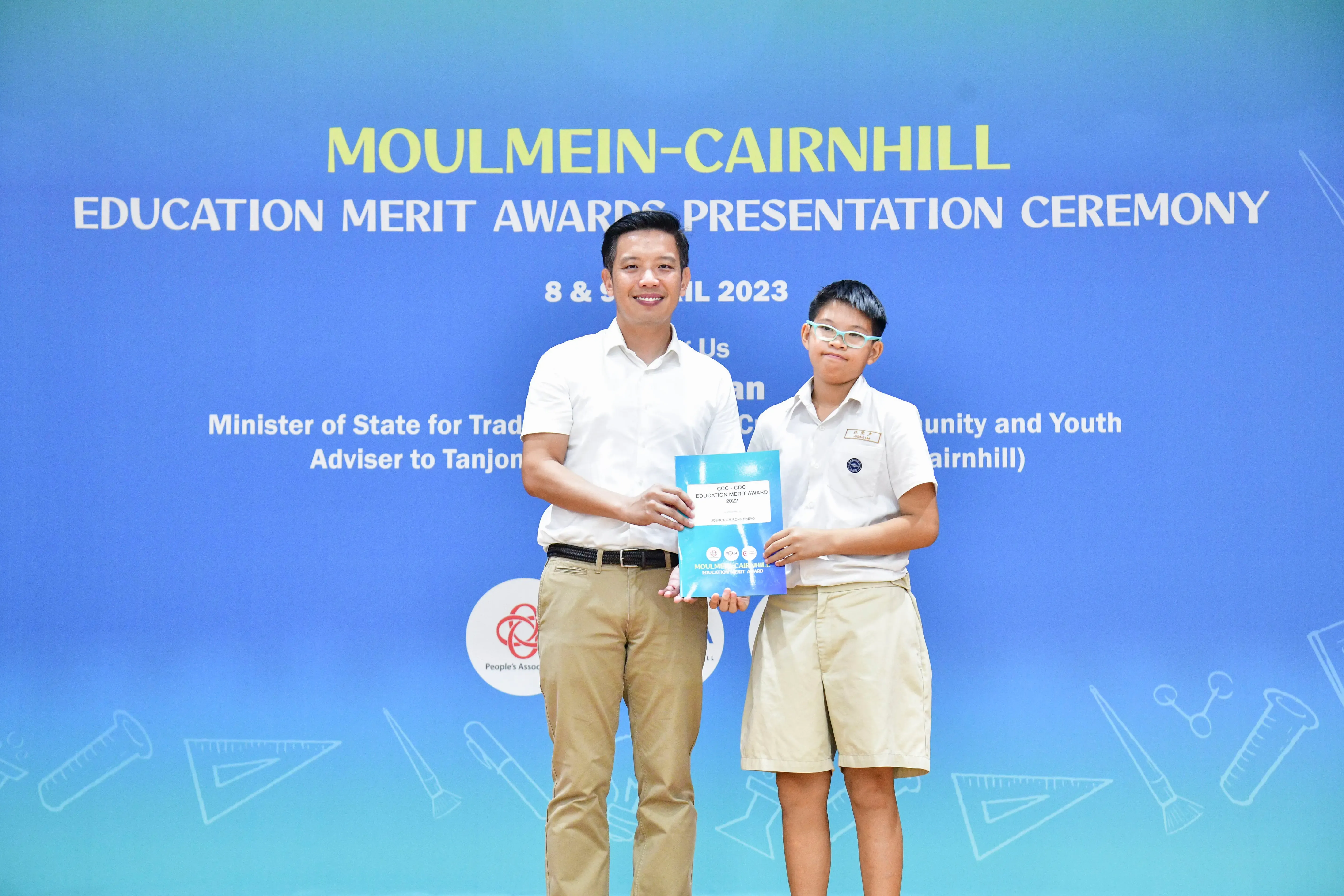 Adult man and young boy holding an award certificate at the Moulmein-Cairnhill Education Merit Awards 2023.