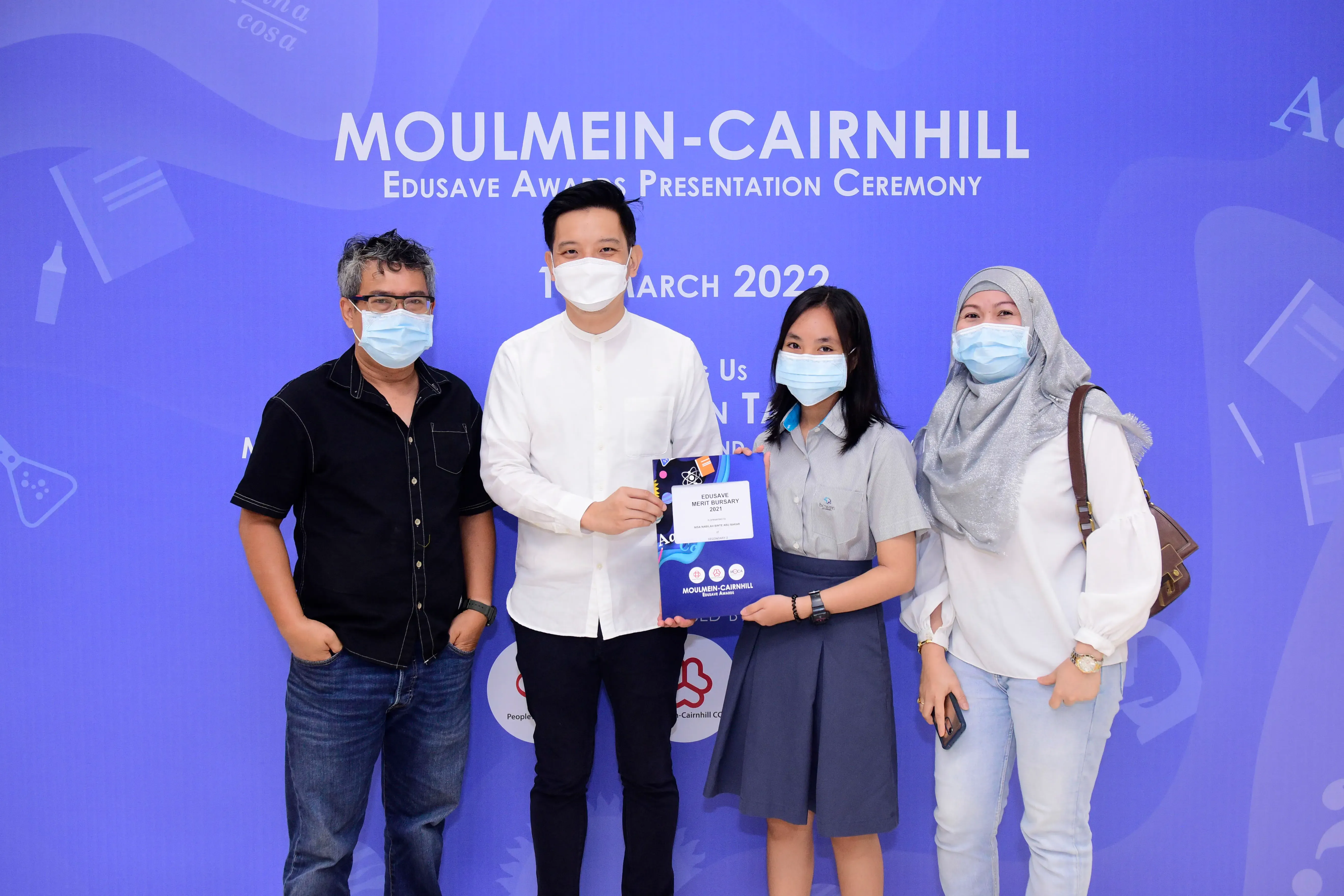 Four masked people pose at the Moulmein-Cairnhill Edusave Awards Presentation Ceremony in March 2022.