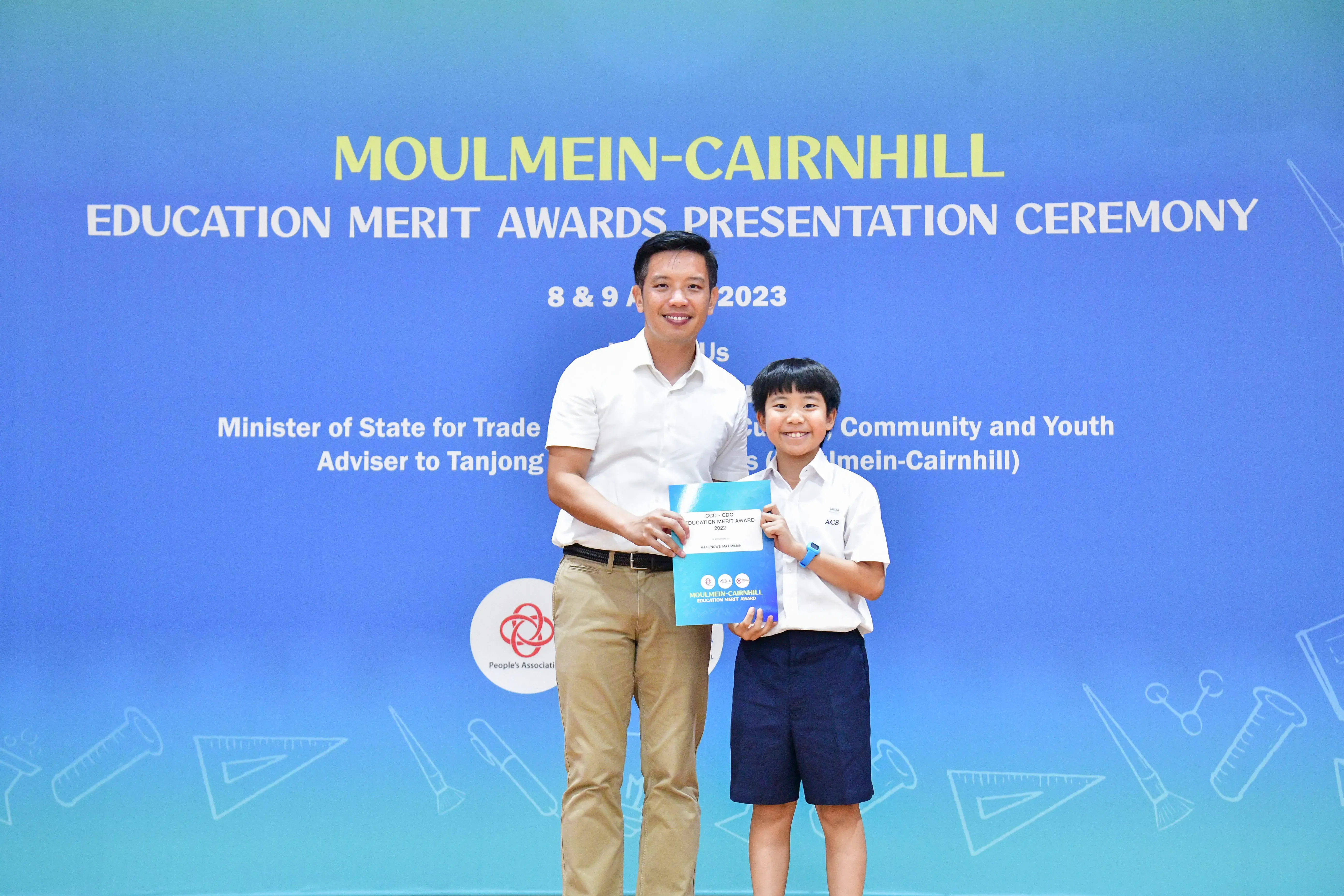 Adult and young student holding an award certificate at the Moulmein-Cairnhill Education Merit Awards Ceremony 2023.