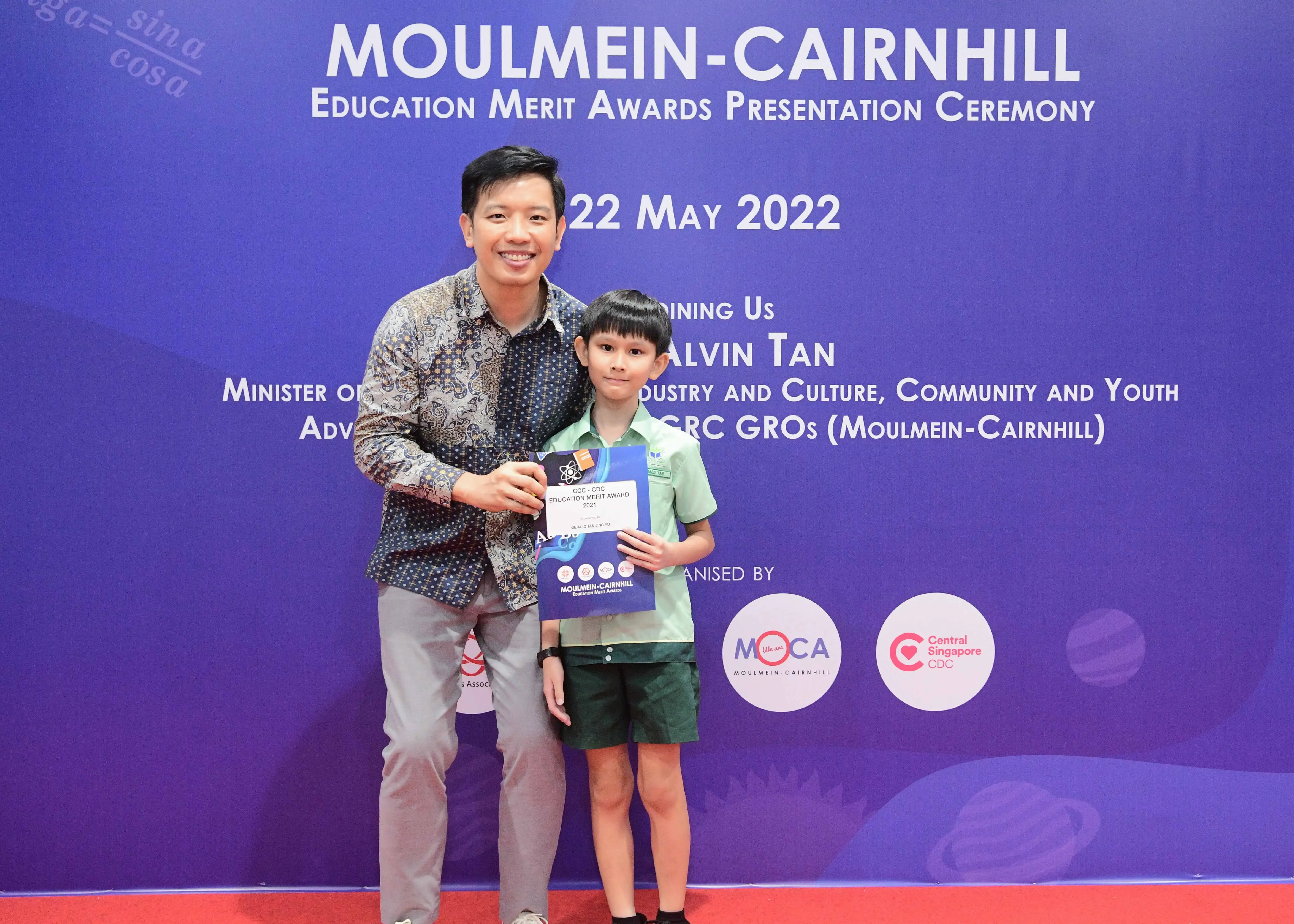 Man and young boy holding an award certificate at Moulmein-Cairnhill Education Merit Awards, 22 May 2022.