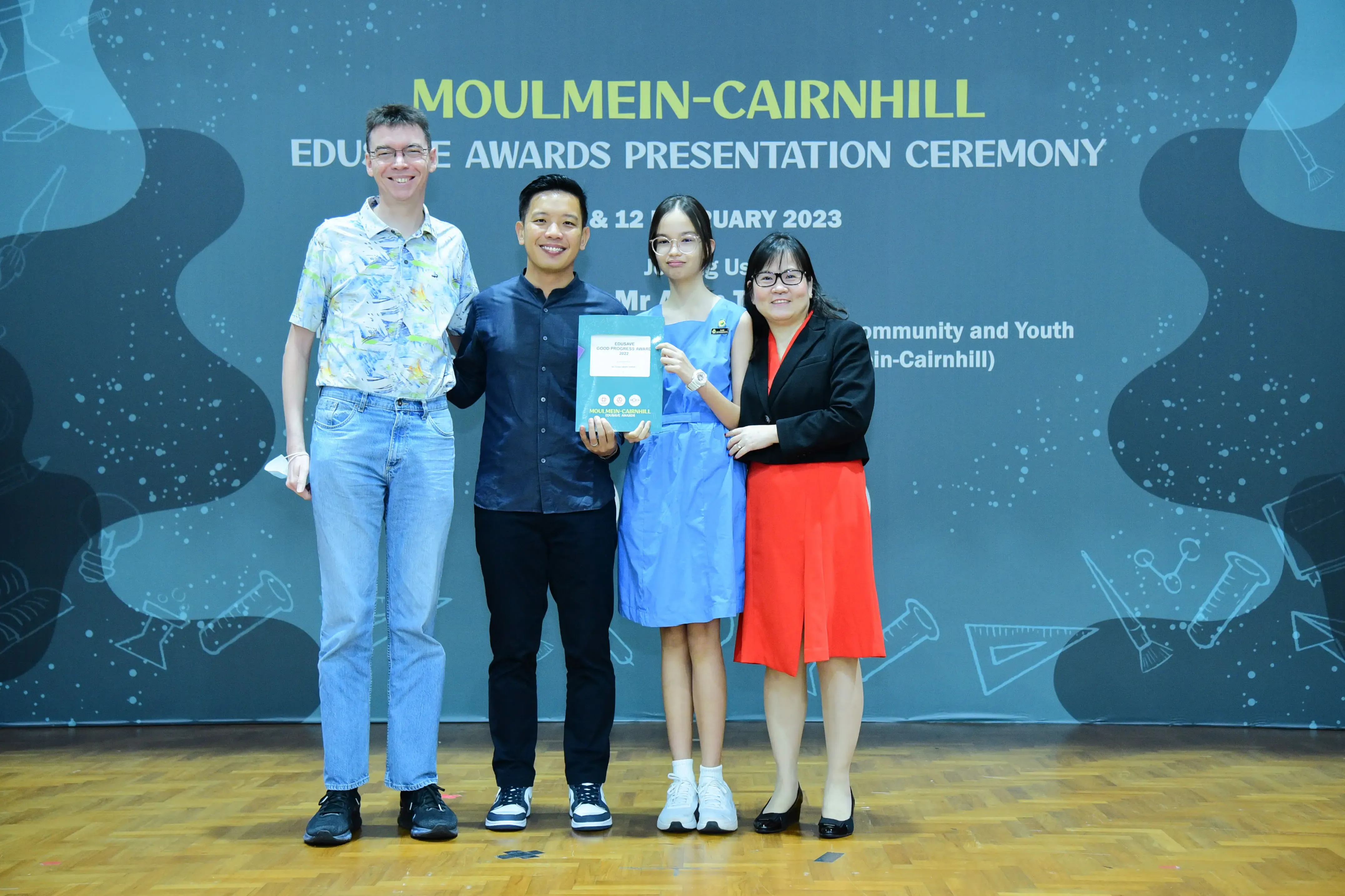 Four people pose at the Moulmein-Cairnhill Edusave Awards Presentation Ceremony 2023, holding a certificate.