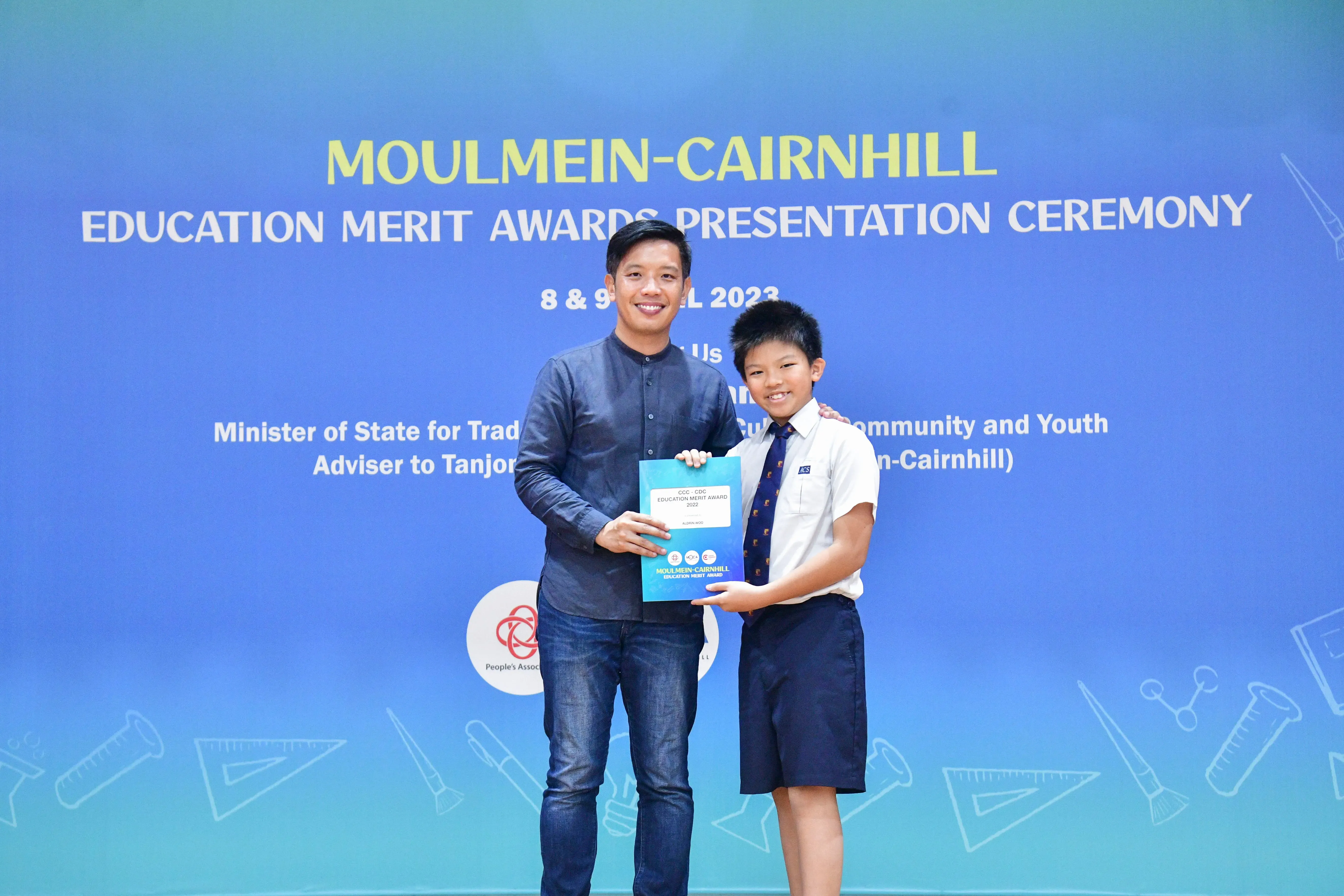 Adult and young student holding a certificate together at the Moulmein-Cairnhill Education Merit Awards 2023.