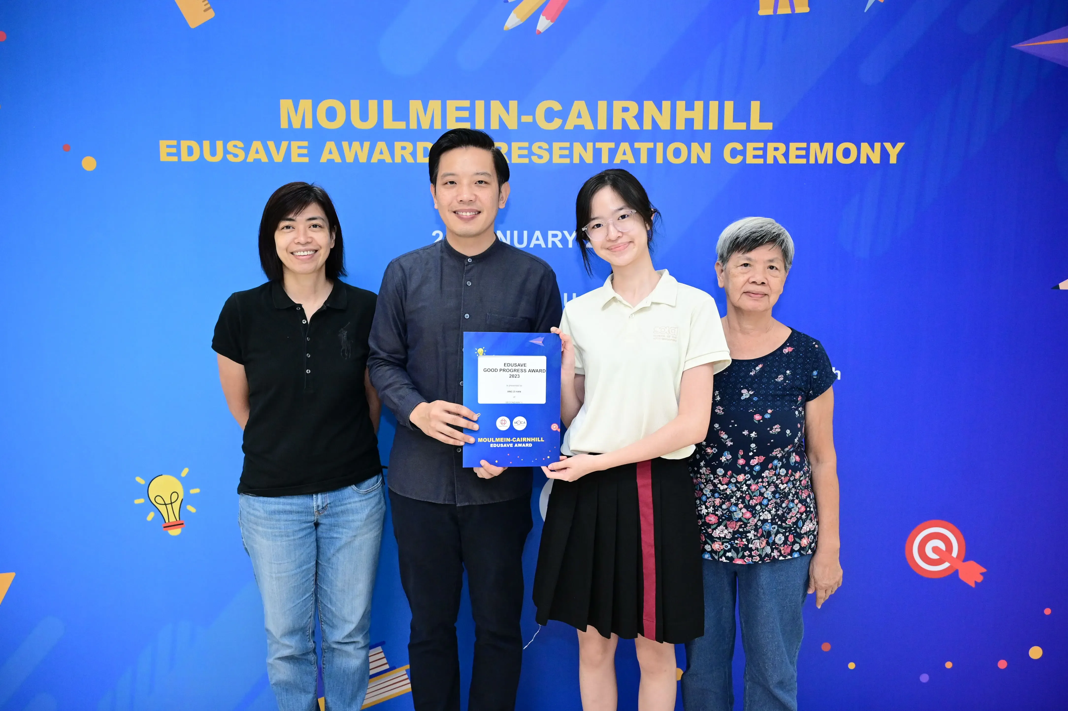 Four people pose holding an Edusave Good Progress Award certificate at the Moulmein-Cairnhill Edusave Award Presentation Ceremony.