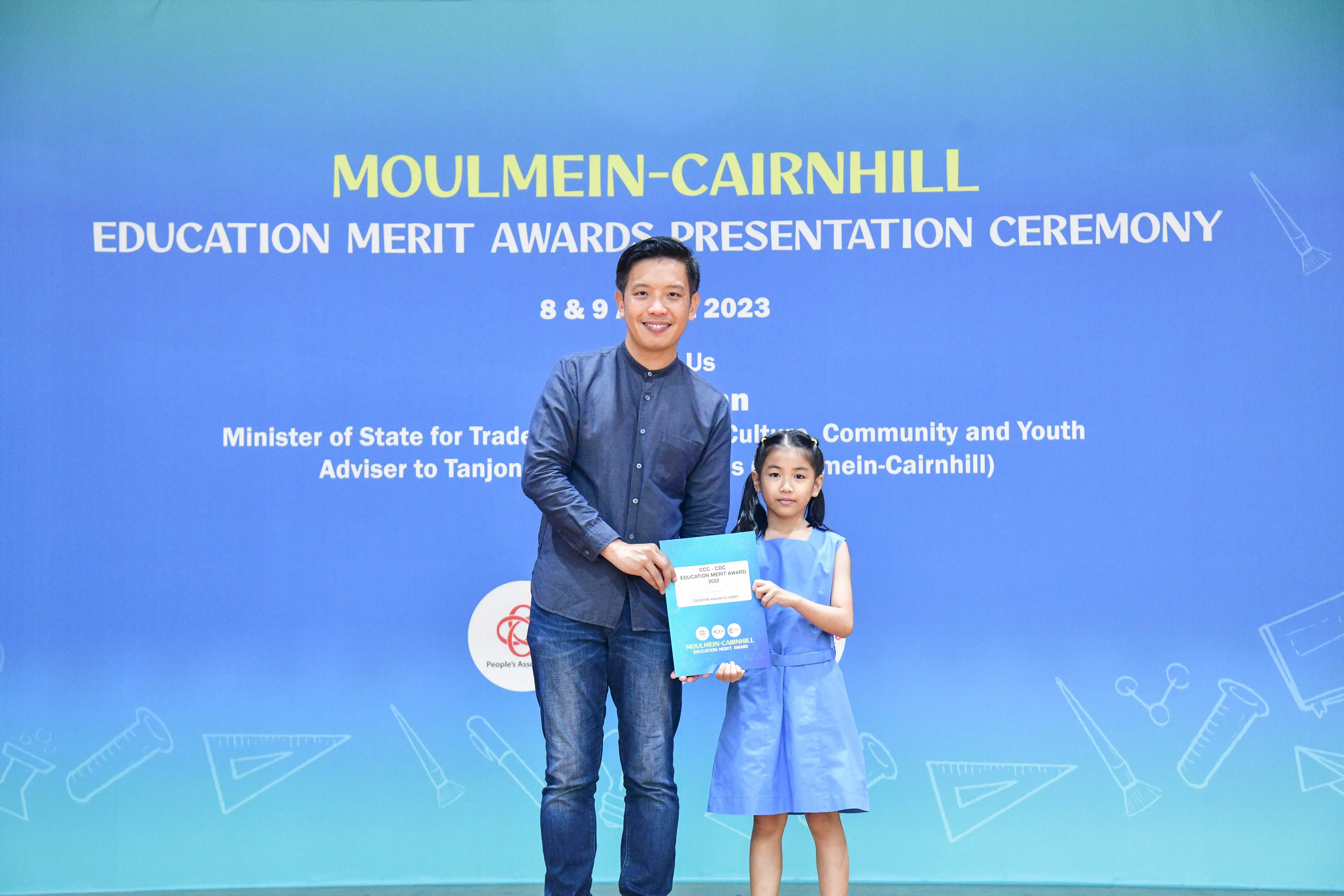 A man and a young girl hold an award certificate at the Moulmein-Cairnhill Education Merit Awards 2023.