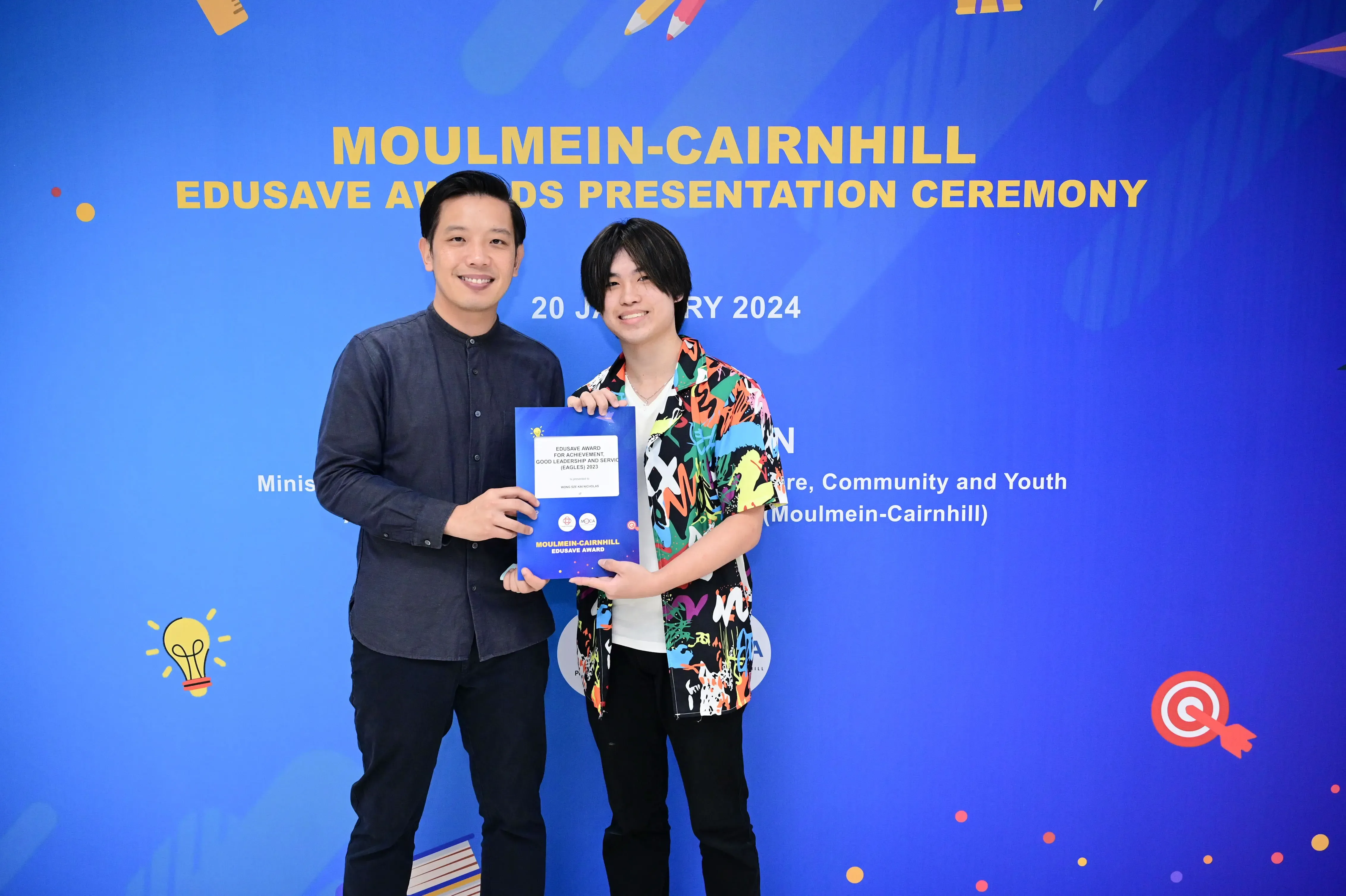 Two smiling men hold an award certificate at the Moulmein-Cairnhill Edusave Awards Presentation Ceremony on 20 January 2024.