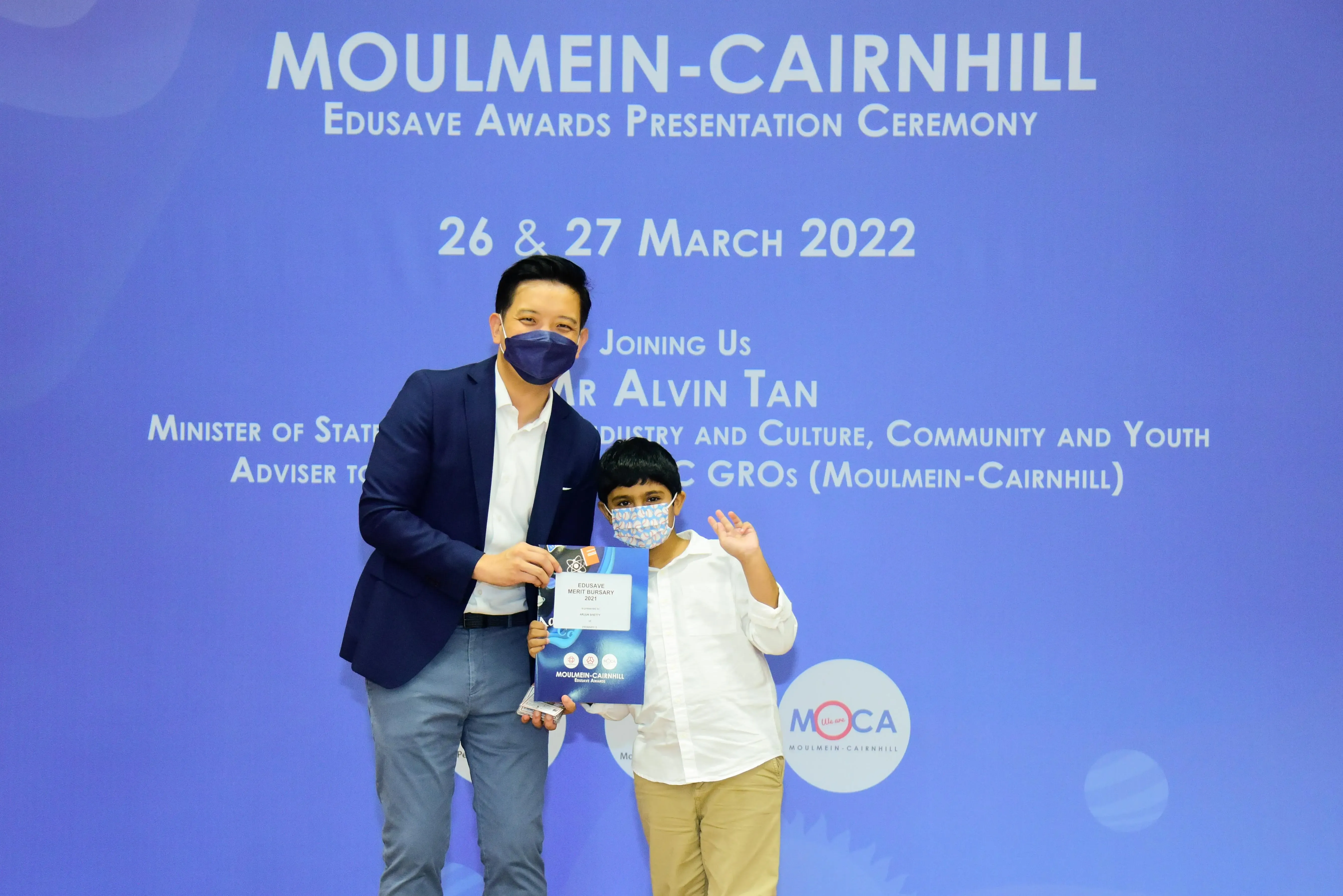 An adult and a child wearing masks pose with an award certificate at the Moulmein-Cairnhill Edusave Awards Ceremony 2022.