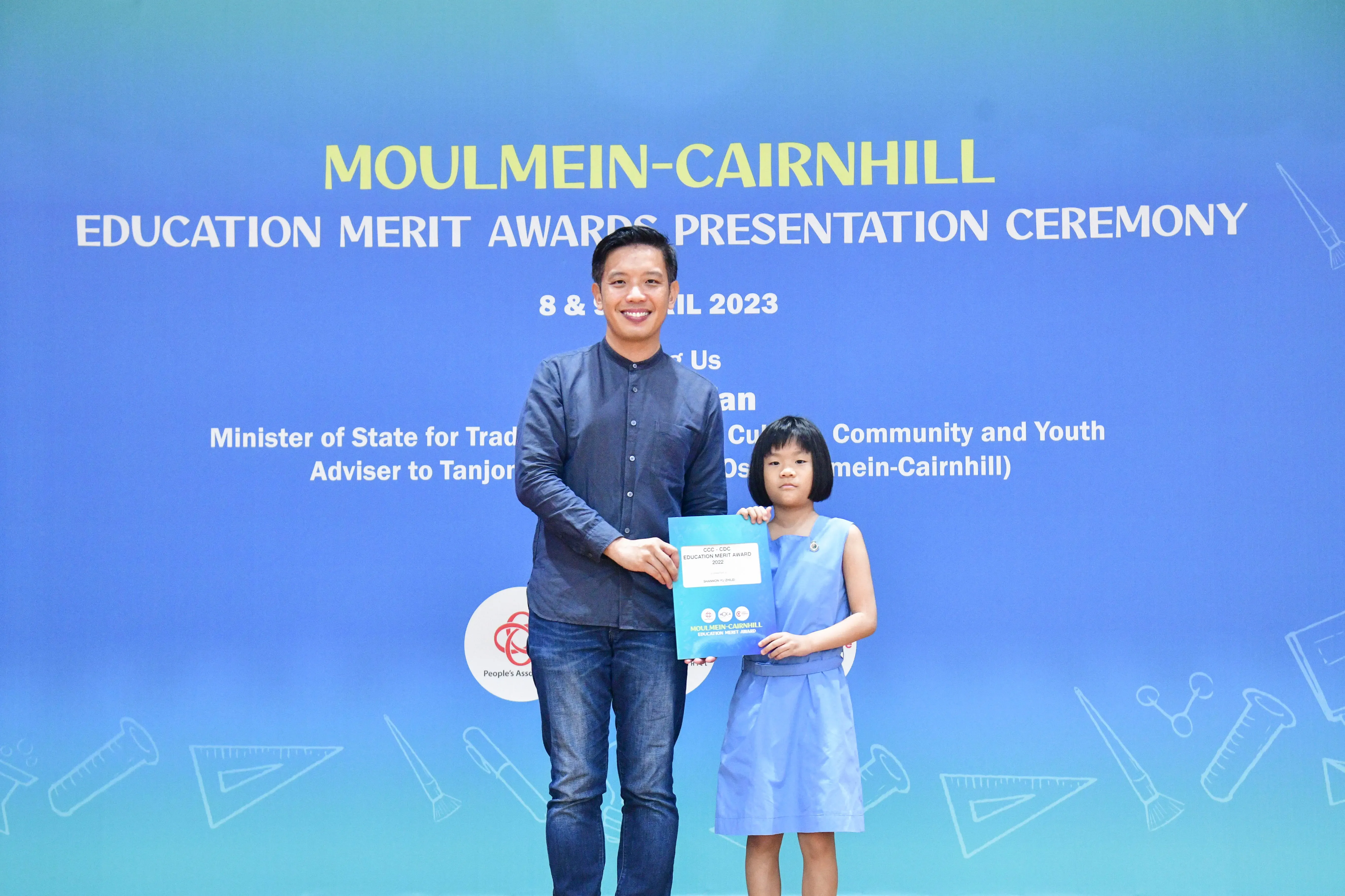 A man and a young girl hold a certificate at the Moulmein-Cairnhill Education Merit Awards Ceremony, April 2023.