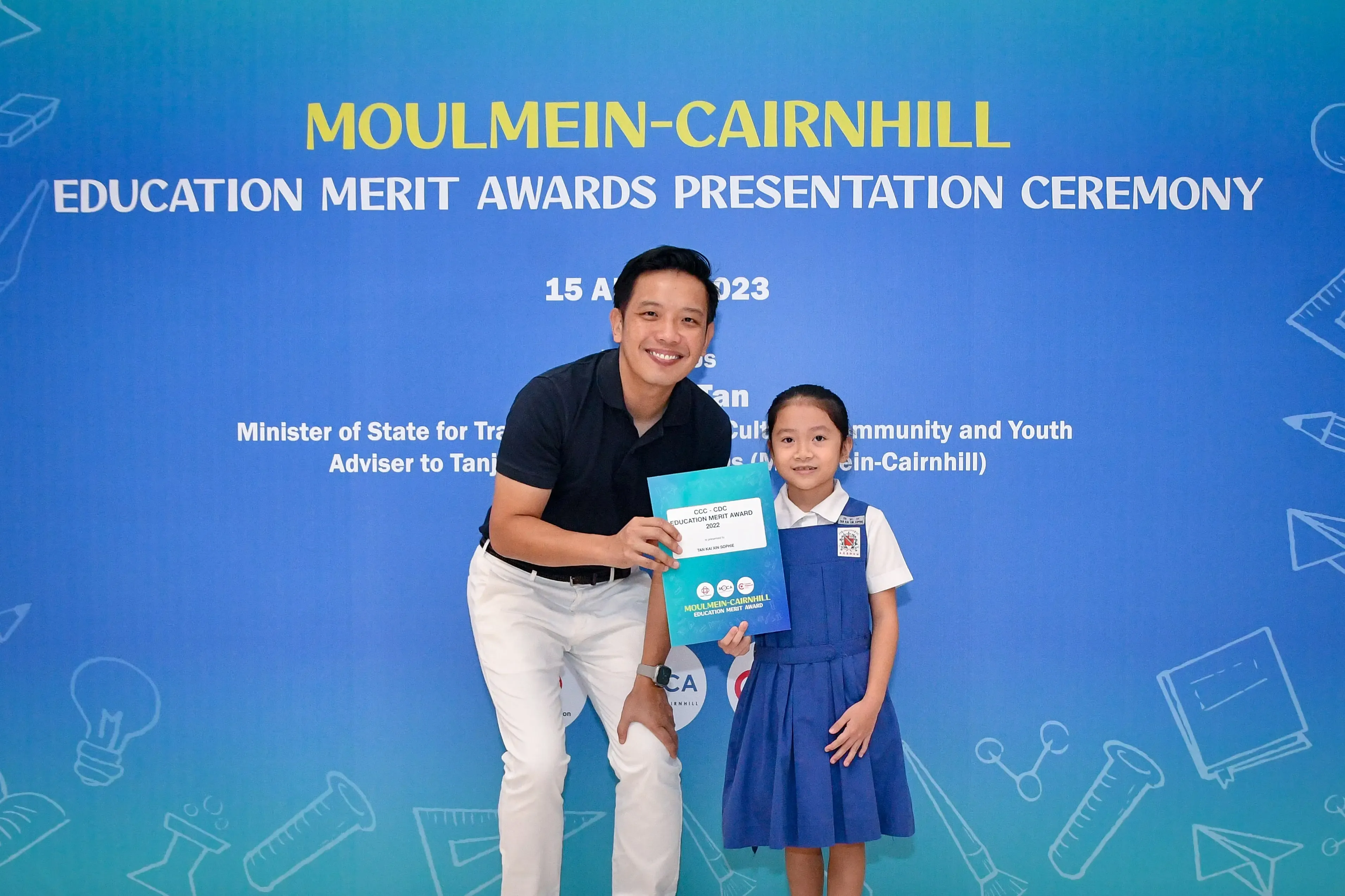 Man and young girl holding an award certificate at the Moulmein-Cairnhill Education Merit Awards Ceremony 2023.