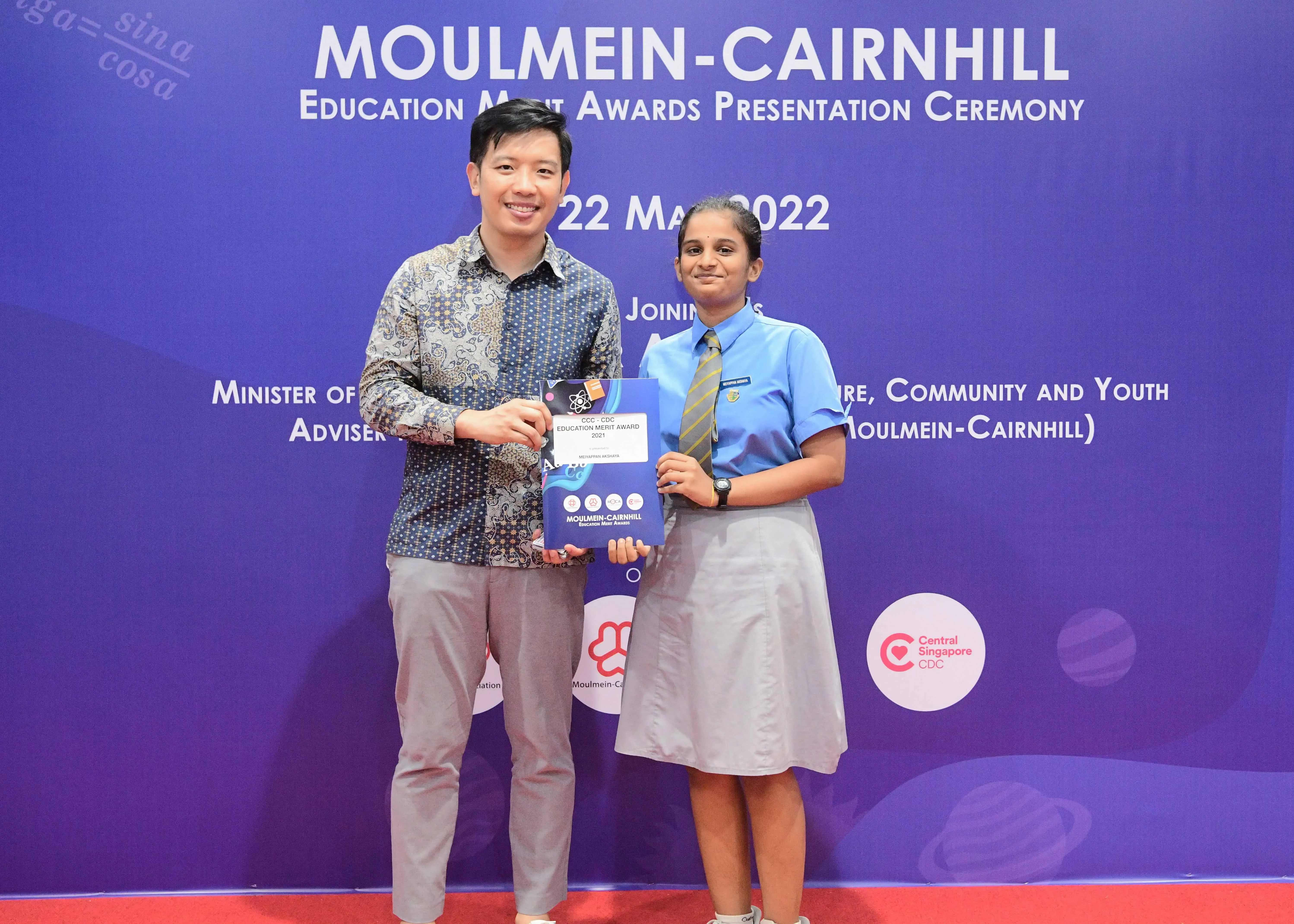 Two people hold an award certificate at the Moulmein-Cairnhill Education Merit Awards Ceremony on 22 May 2022.