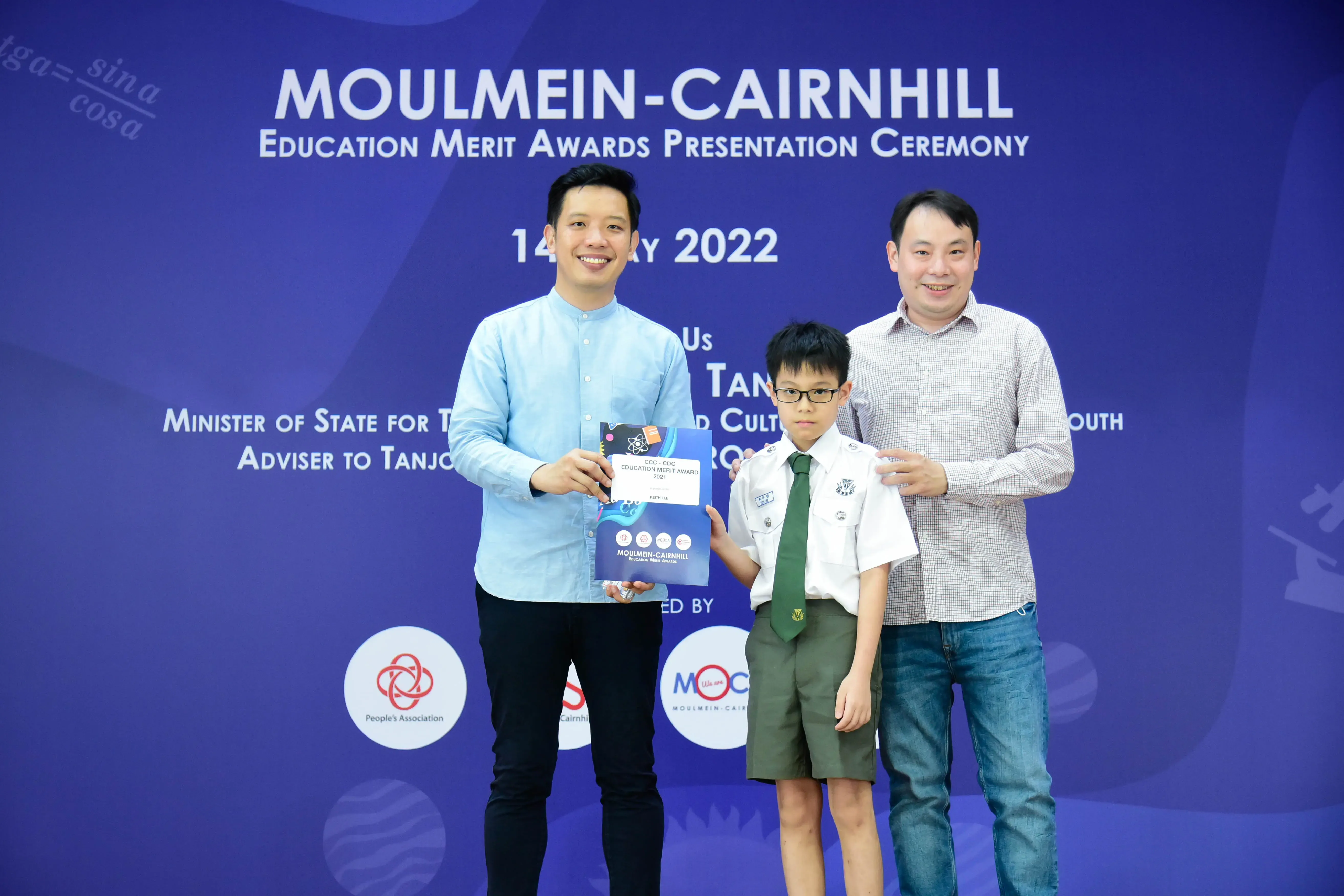 Two men and a uniformed boy pose at the Moulmein-Cairnhill Education Merit Awards Ceremony 2022.