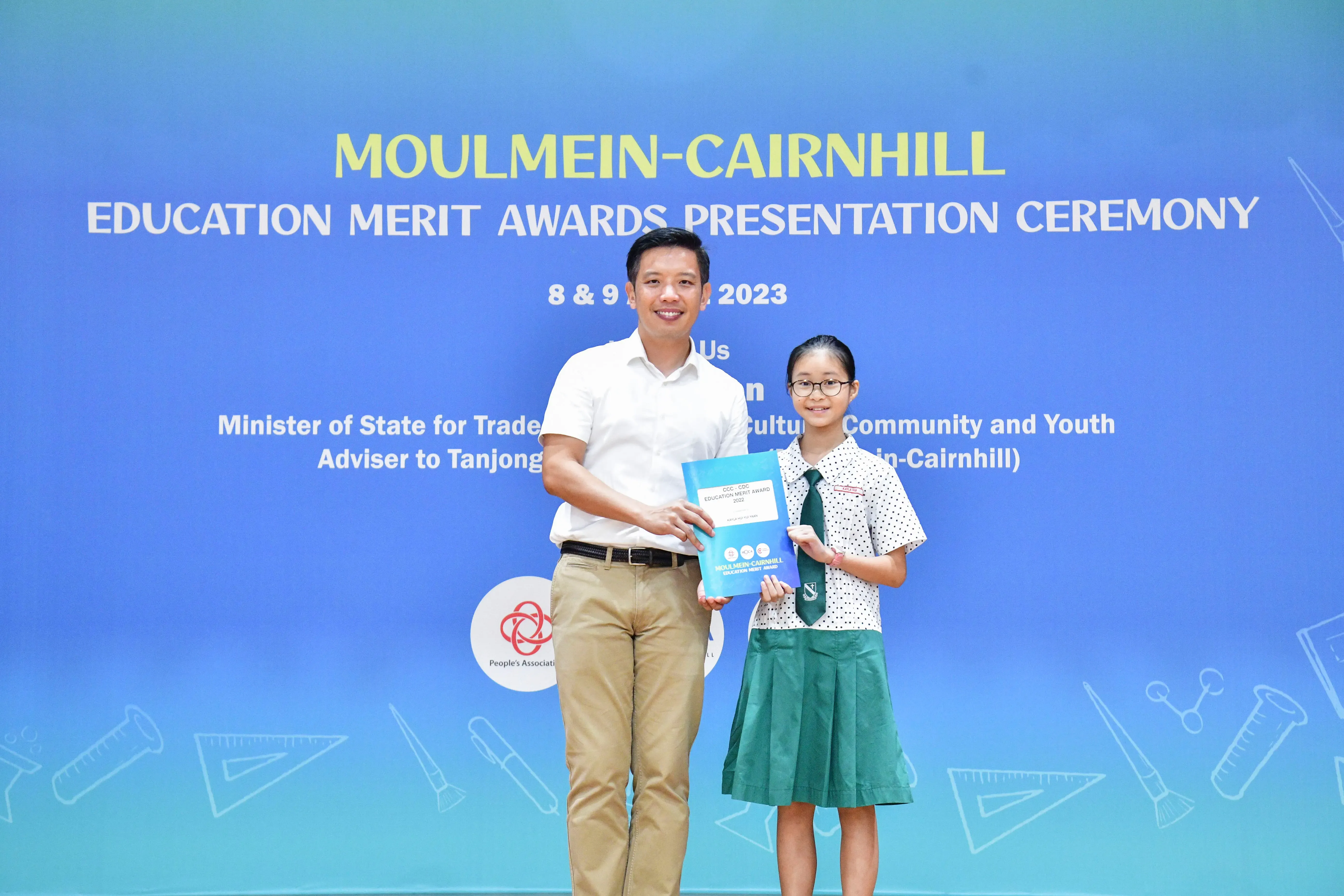 A man and a young girl in school uniform hold an award together at the Moulmein-Cairnhill Education Merit Awards 2023.