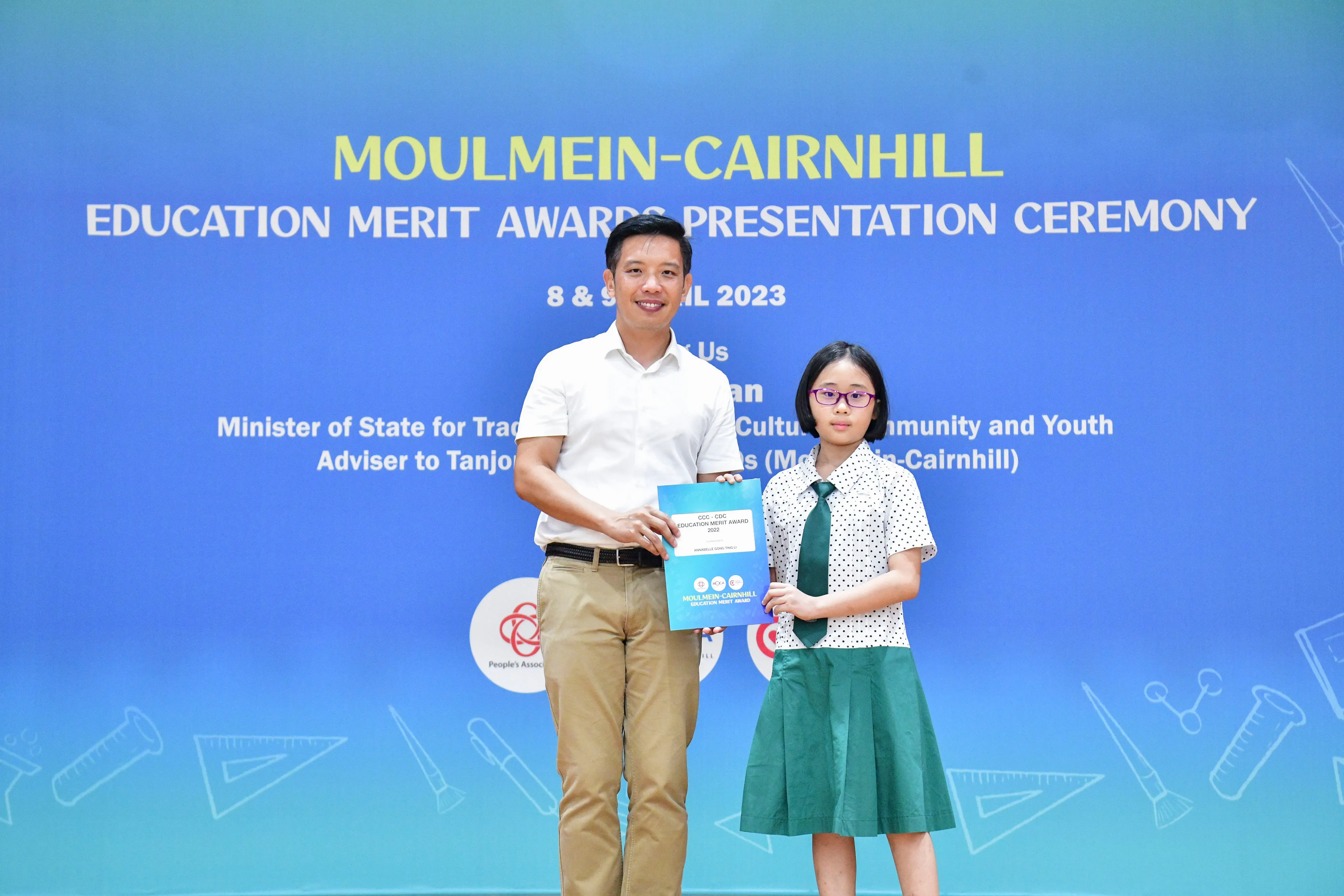 A man and a young girl in school uniform hold an award certificate at the Moulmein-Cairnhill Education Merit Awards 2023.