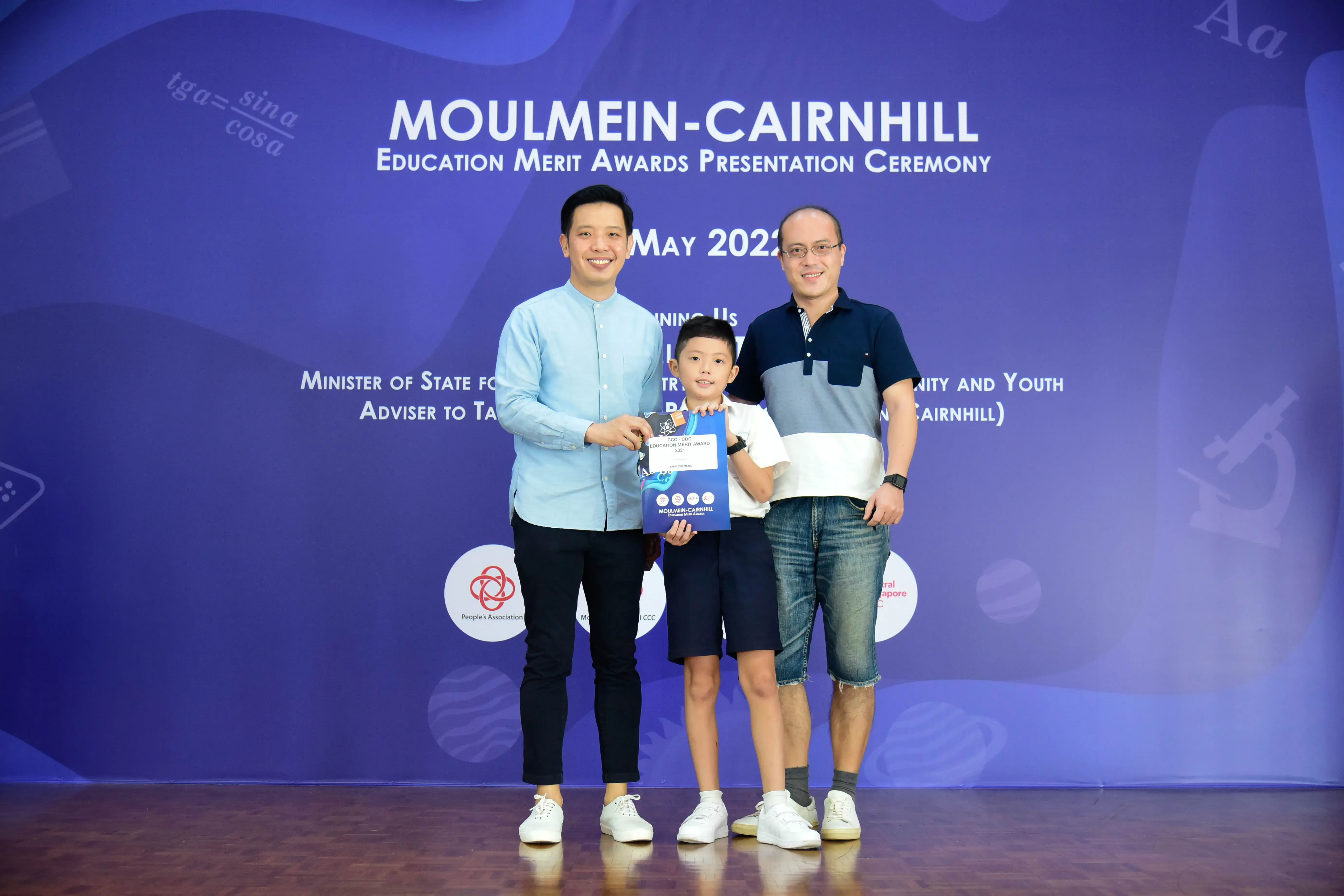 Two men and a young boy pose at the Moulmein-Cairnhill Education Merit Awards Presentation Ceremony, May 2022.