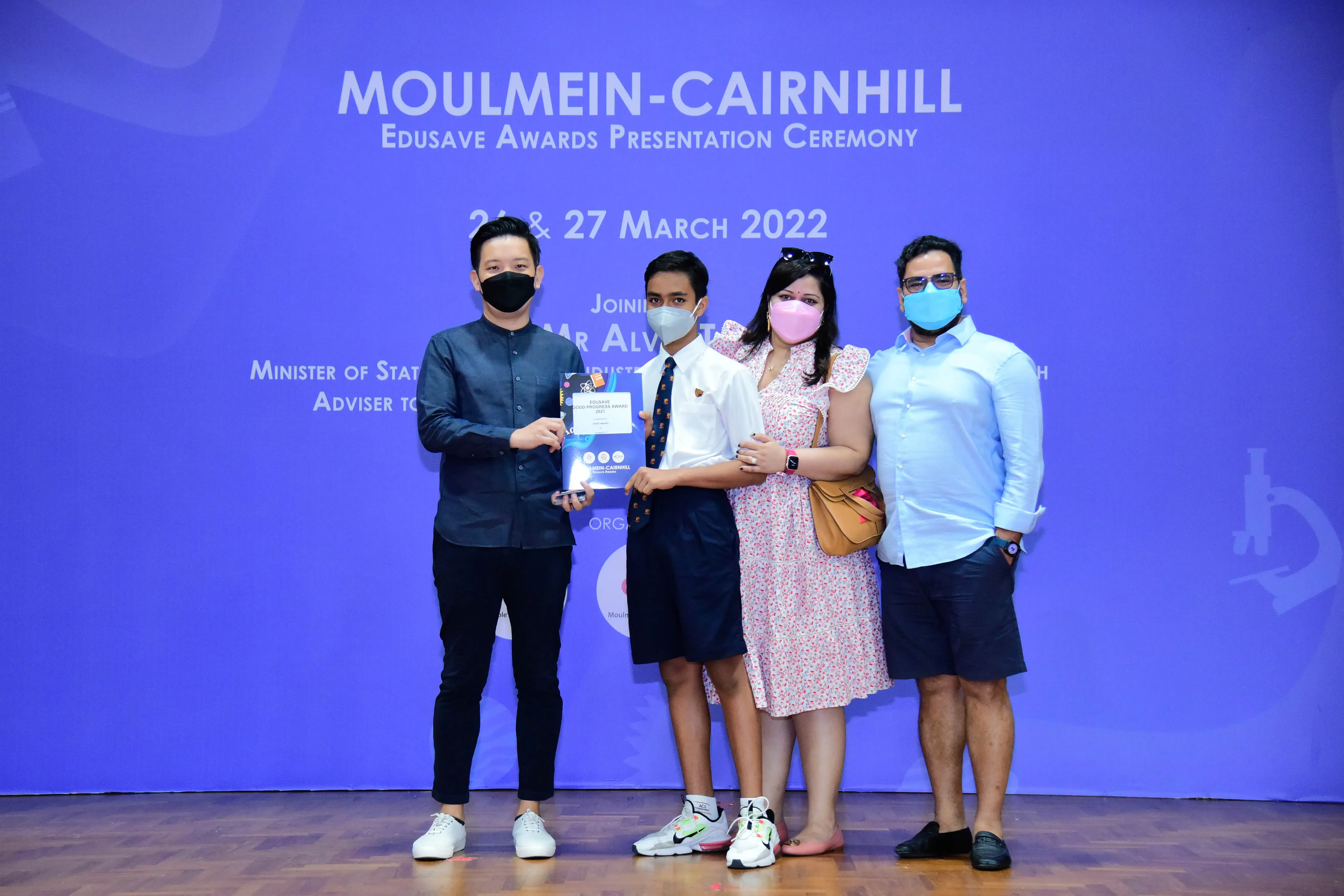 Four masked people pose with a certificate at the Moulmein-Cairnhill Edusave Awards Ceremony, March 2022.