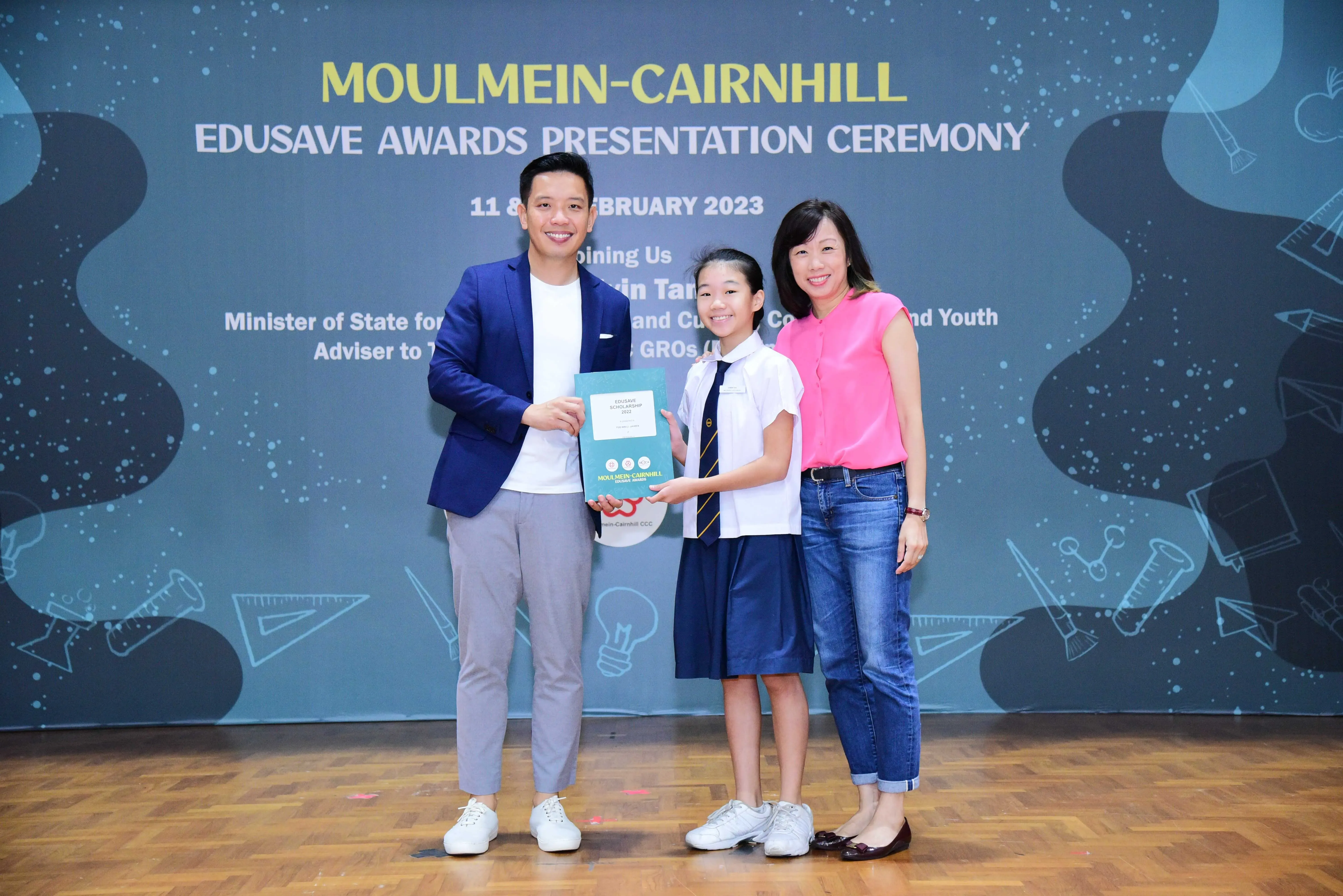 Three people pose holding an award at the Moulmein-Cairnhill Edusave Awards Presentation Ceremony, February 2023.