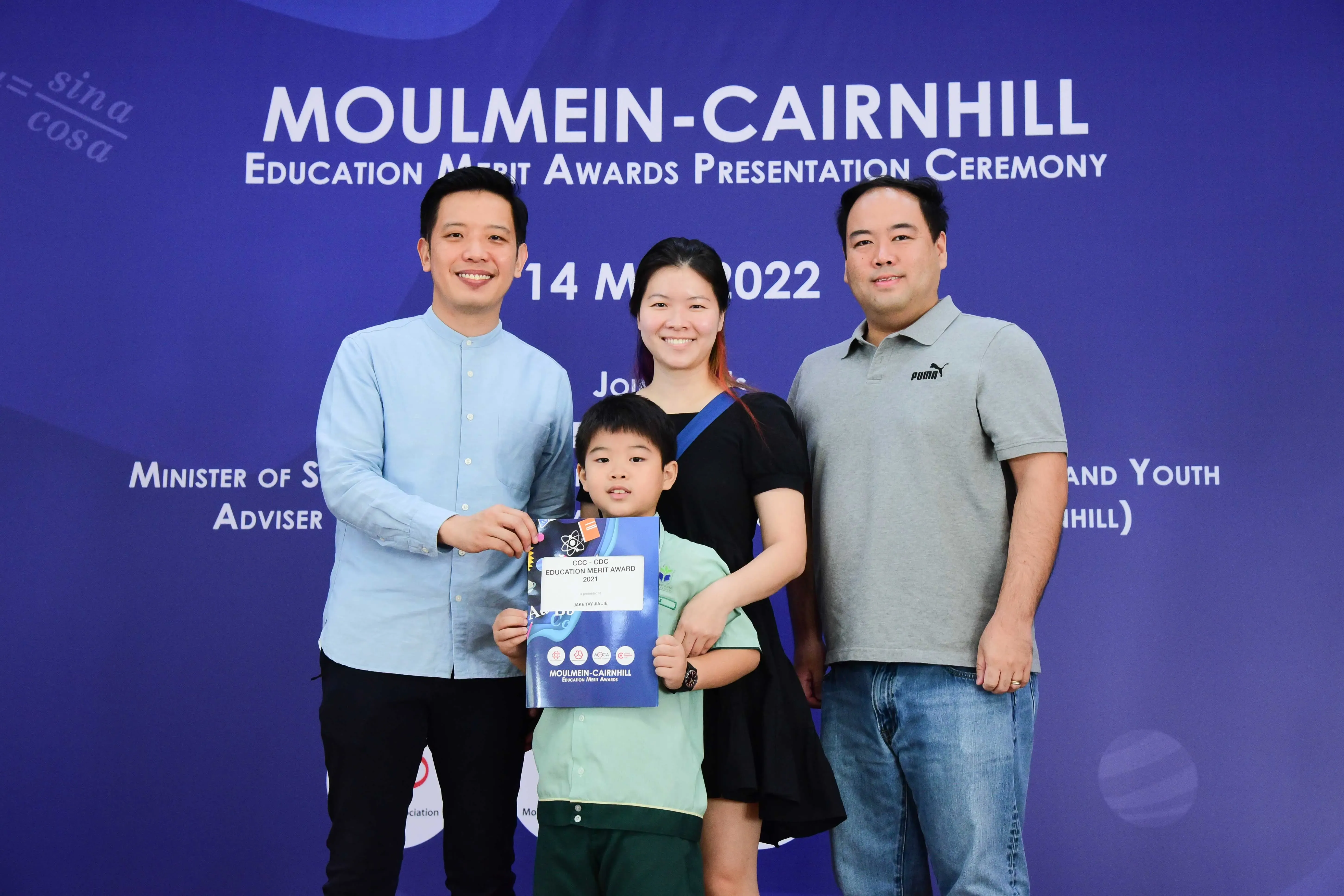 Three adults and a young boy holding an Education Merit Award certificate at the Moulmein-Cairnhill ceremony in 2022.