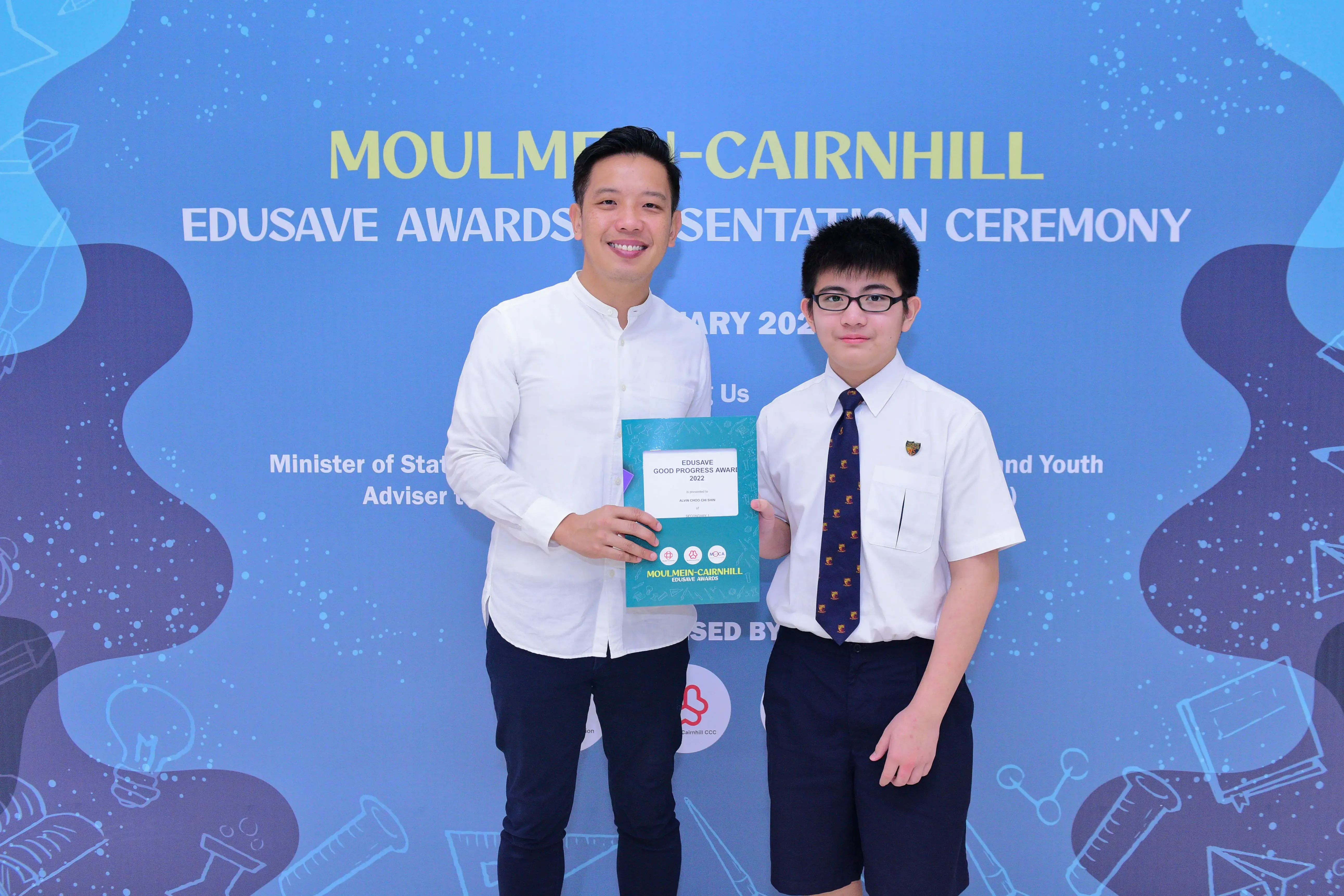 Two people pose holding an Edusave Good Progress Award certificate at the Moulmein-Cairnhill Edusave Awards Presentation Ceremony.