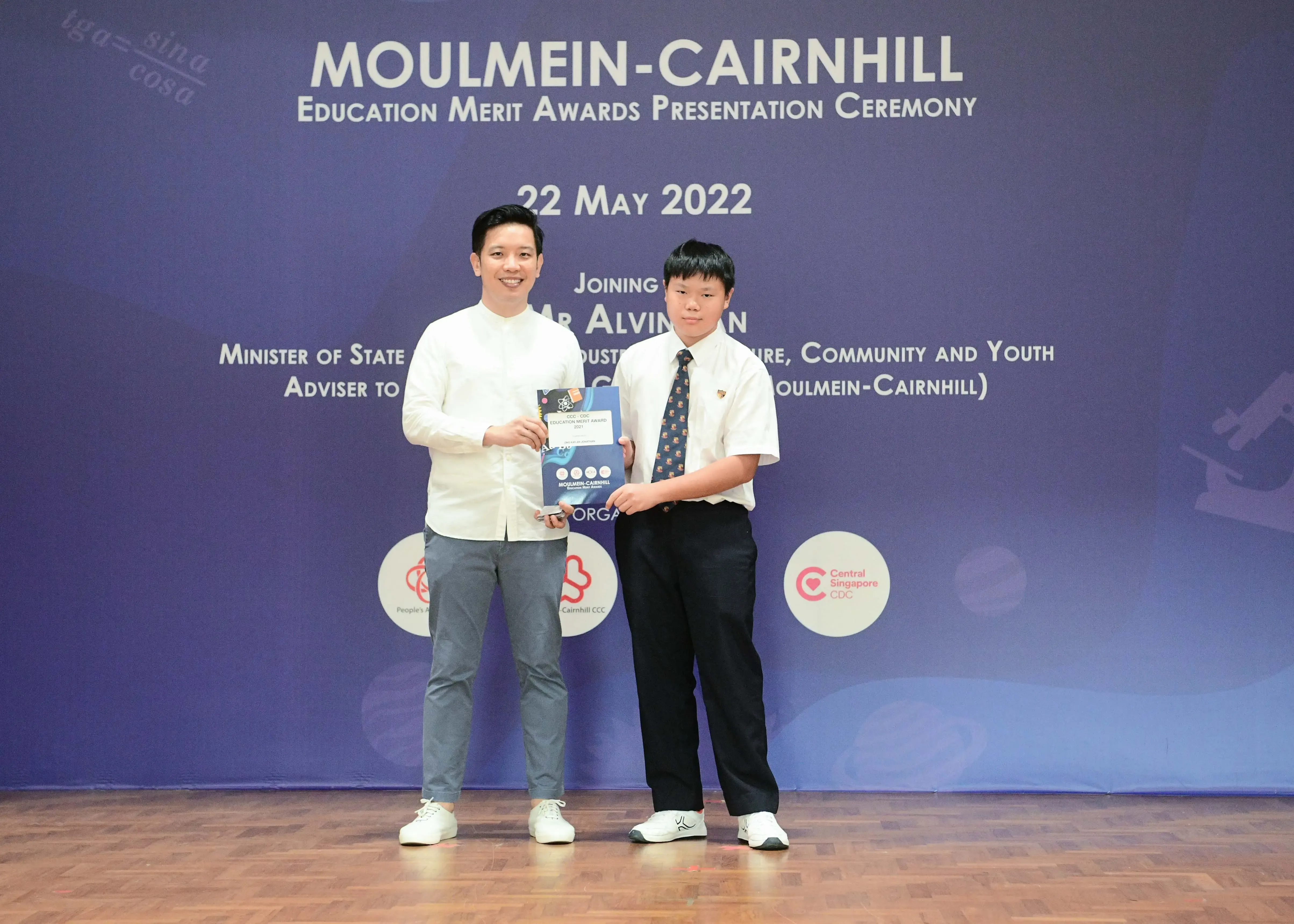 Two people hold an award certificate at the Moulmein-Cairnhill Education Merit Awards Ceremony on 22 May 2022.