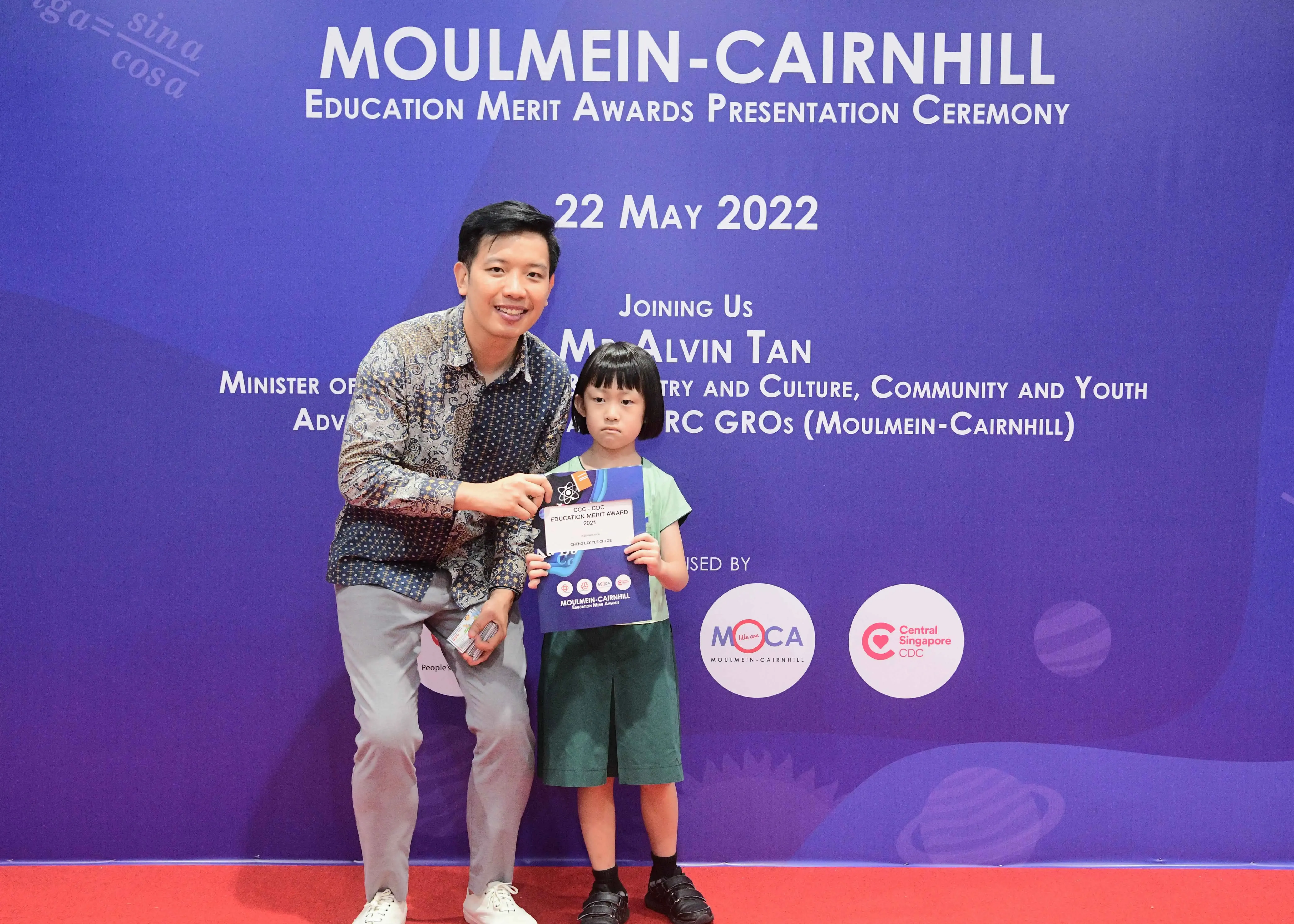 Man and young child pose with an award certificate at the Moulmein-Cairnhill Education Merit Awards, 22 May 2022.