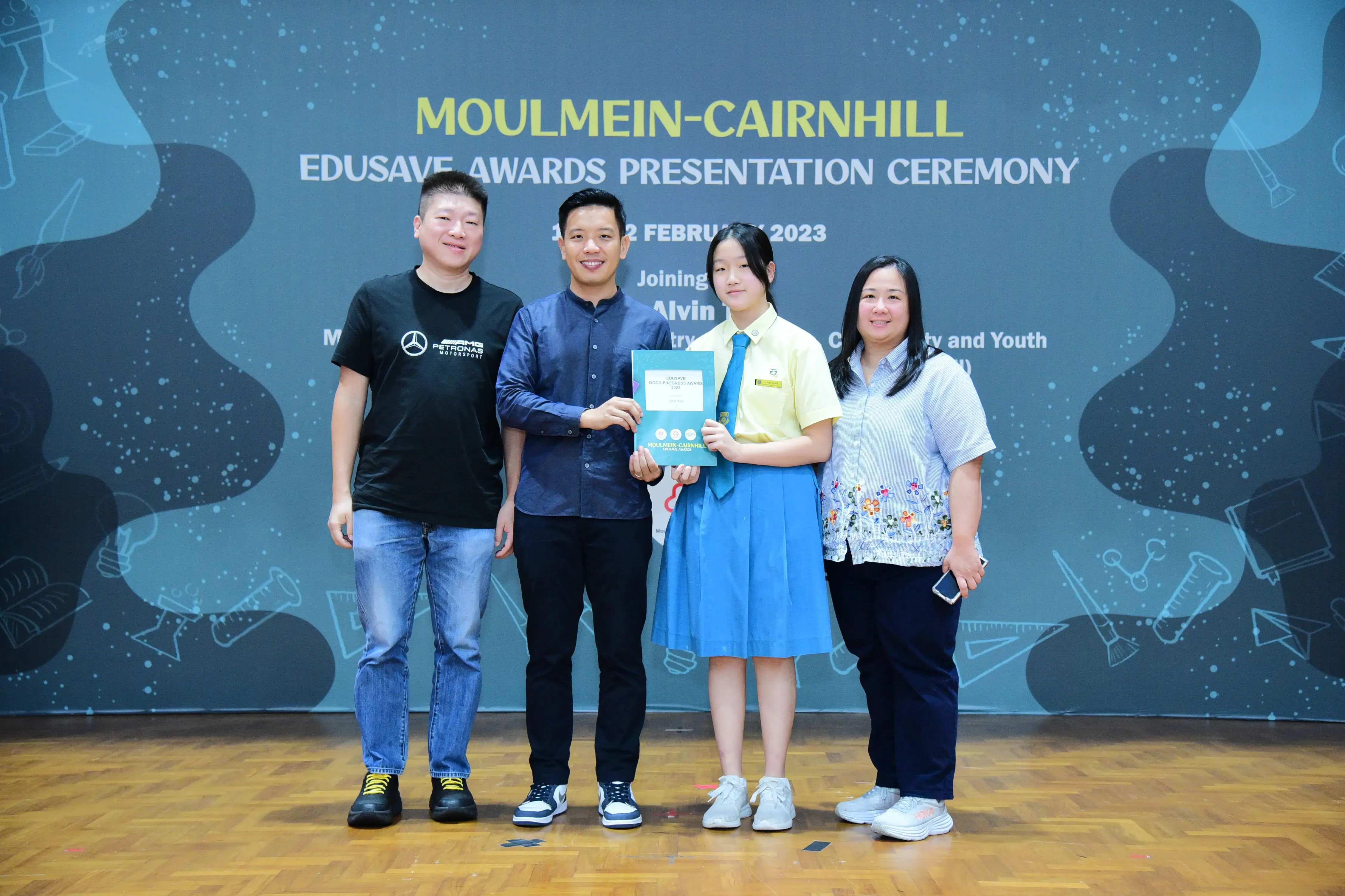 Four people pose on a stage at the Moulmein-Cairnhill Edusave Awards Presentation Ceremony, February 2023.