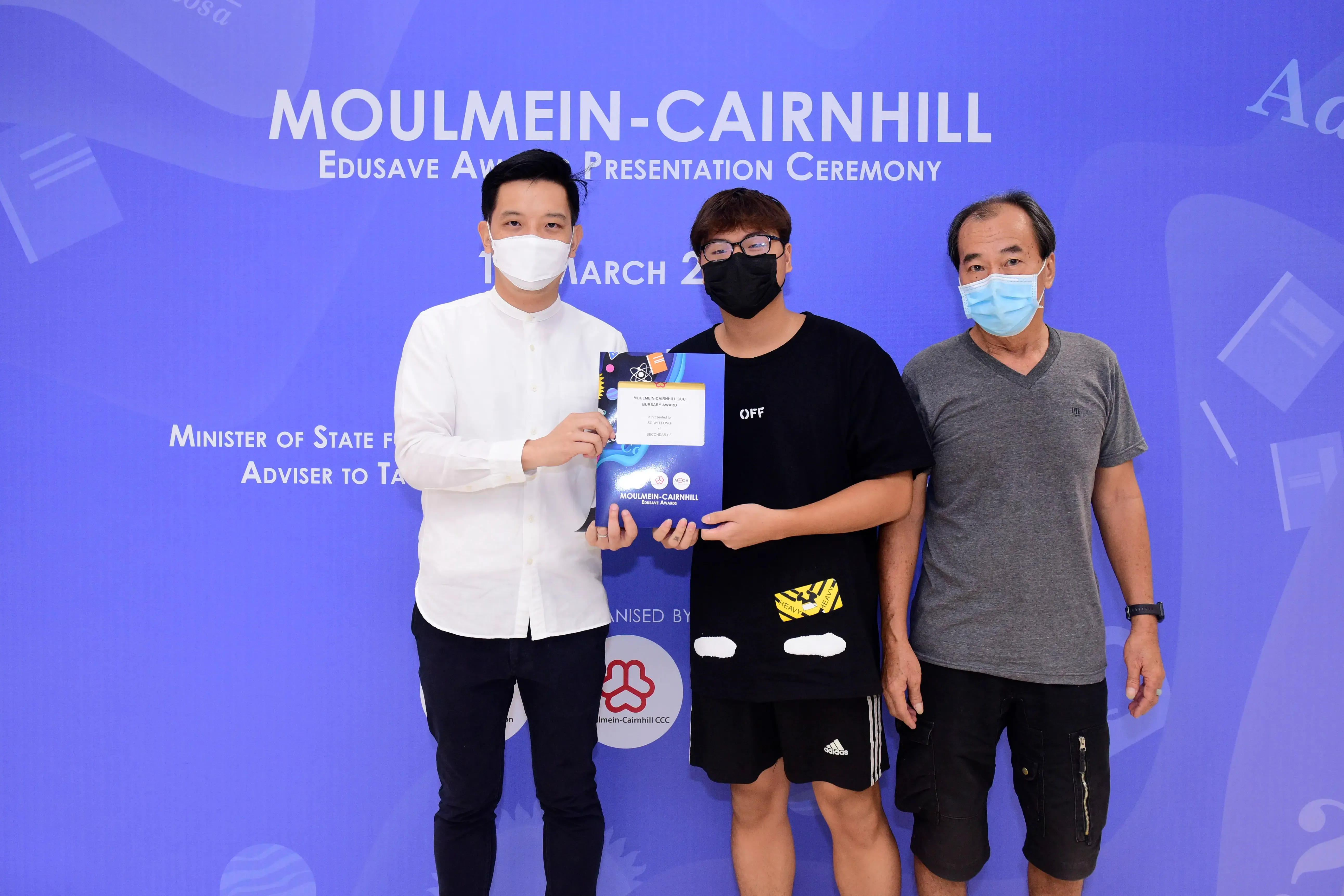 Three masked men pose together holding an award at the Moulmein-Cairnhill Edusave Award Presentation Ceremony.