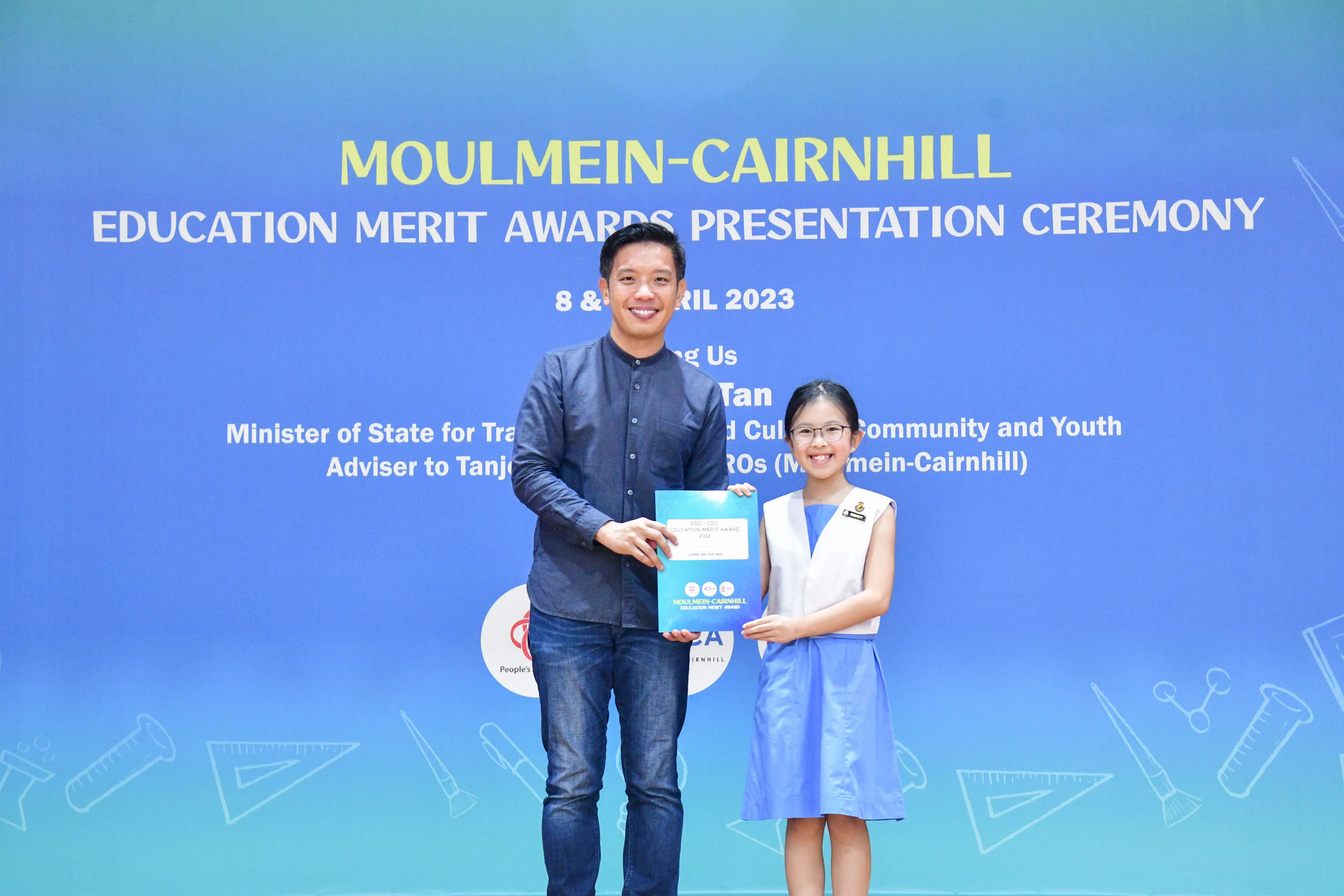 A man and a young girl hold a certificate together at the Moulmein-Cairnhill Education Merit Awards Ceremony 2023.