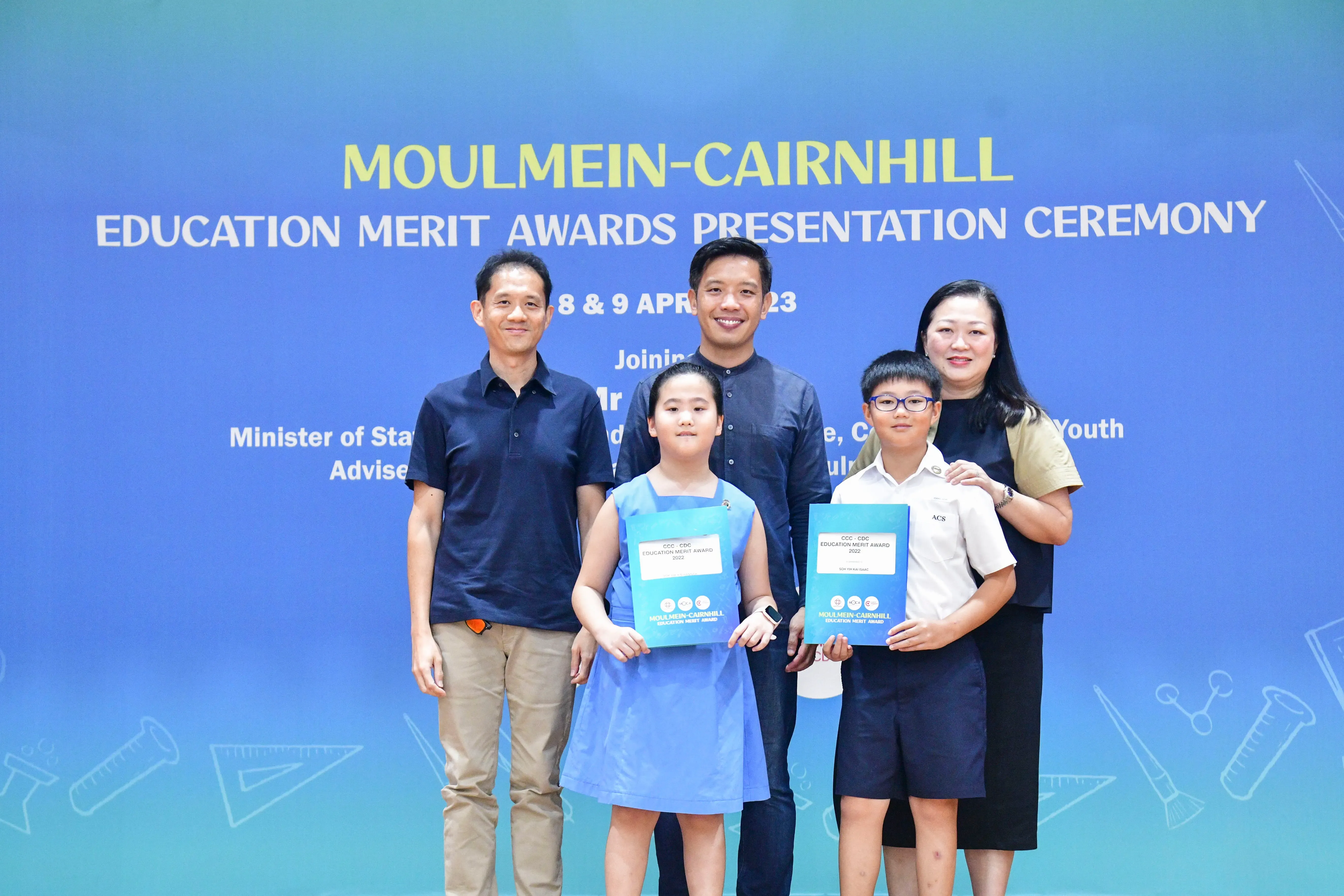Two adults and two children pose with award folders at the Moulmein-Cairnhill Education Merit Awards Ceremony in April 2023.