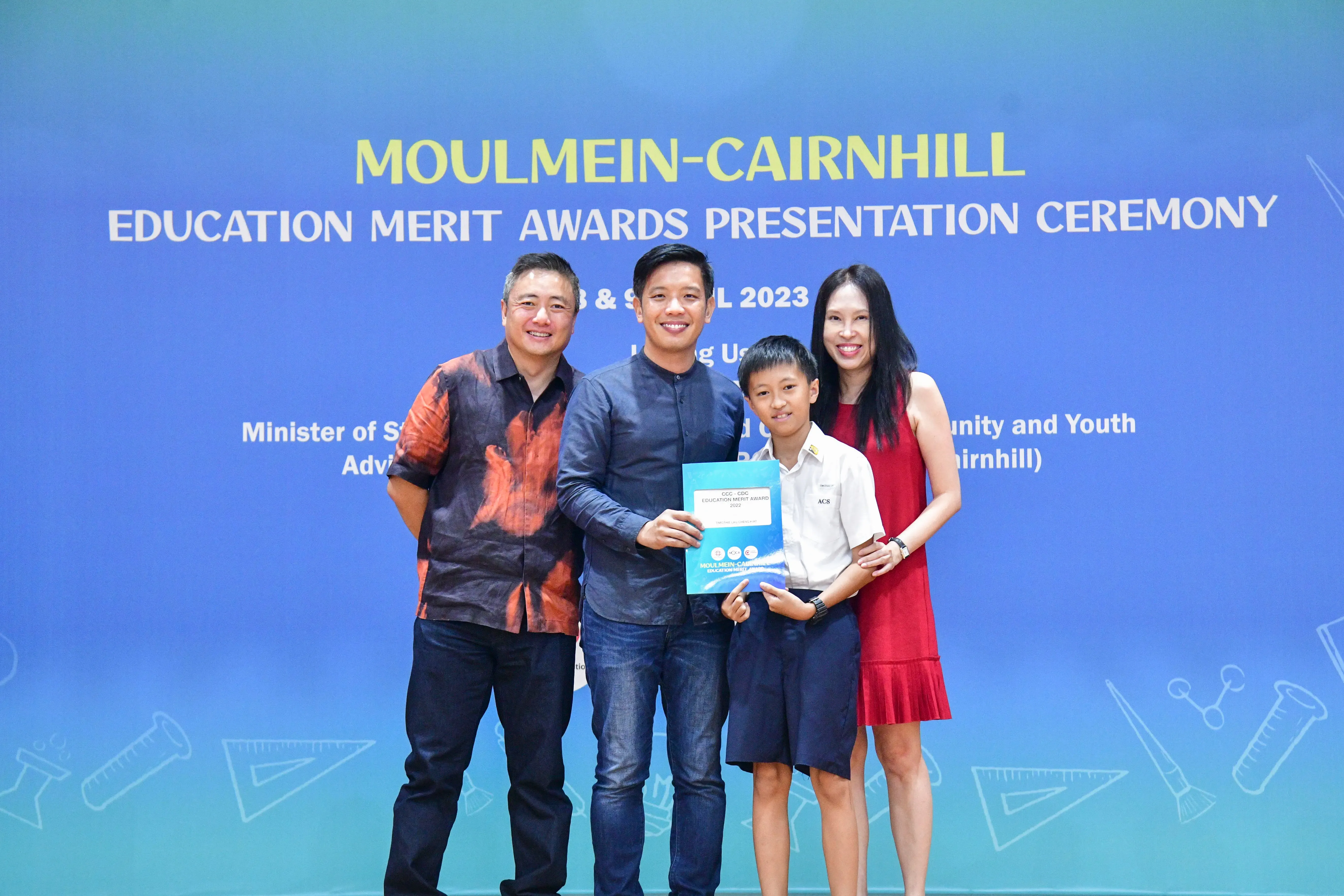 Three adults and a boy hold an award certificate at the Moulmein-Cairnhill Education Merit Awards Ceremony 2023.