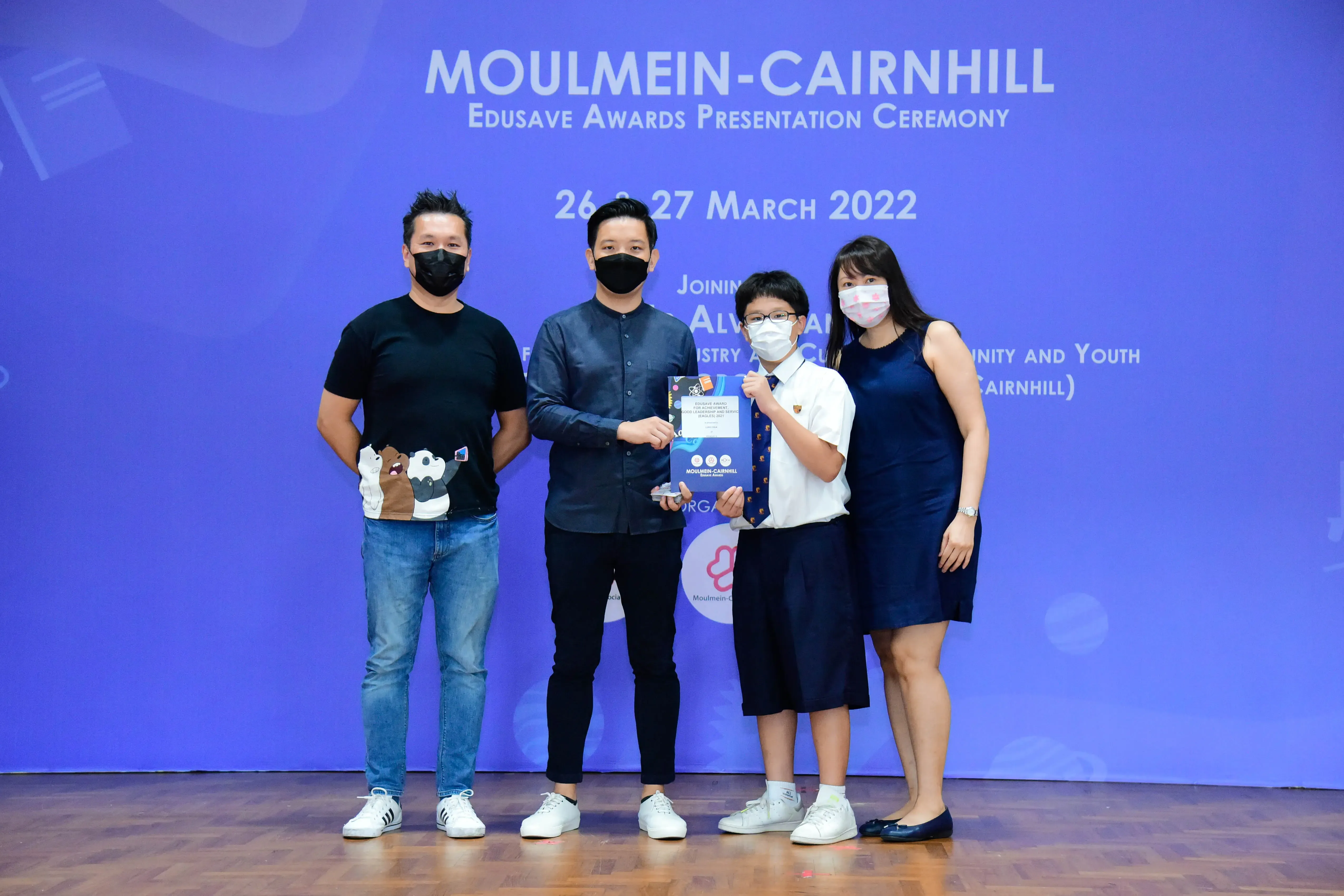 Four masked people pose at the Moulmein-Cairnhill Edusave Awards Presentation Ceremony on 26-27 March 2022.