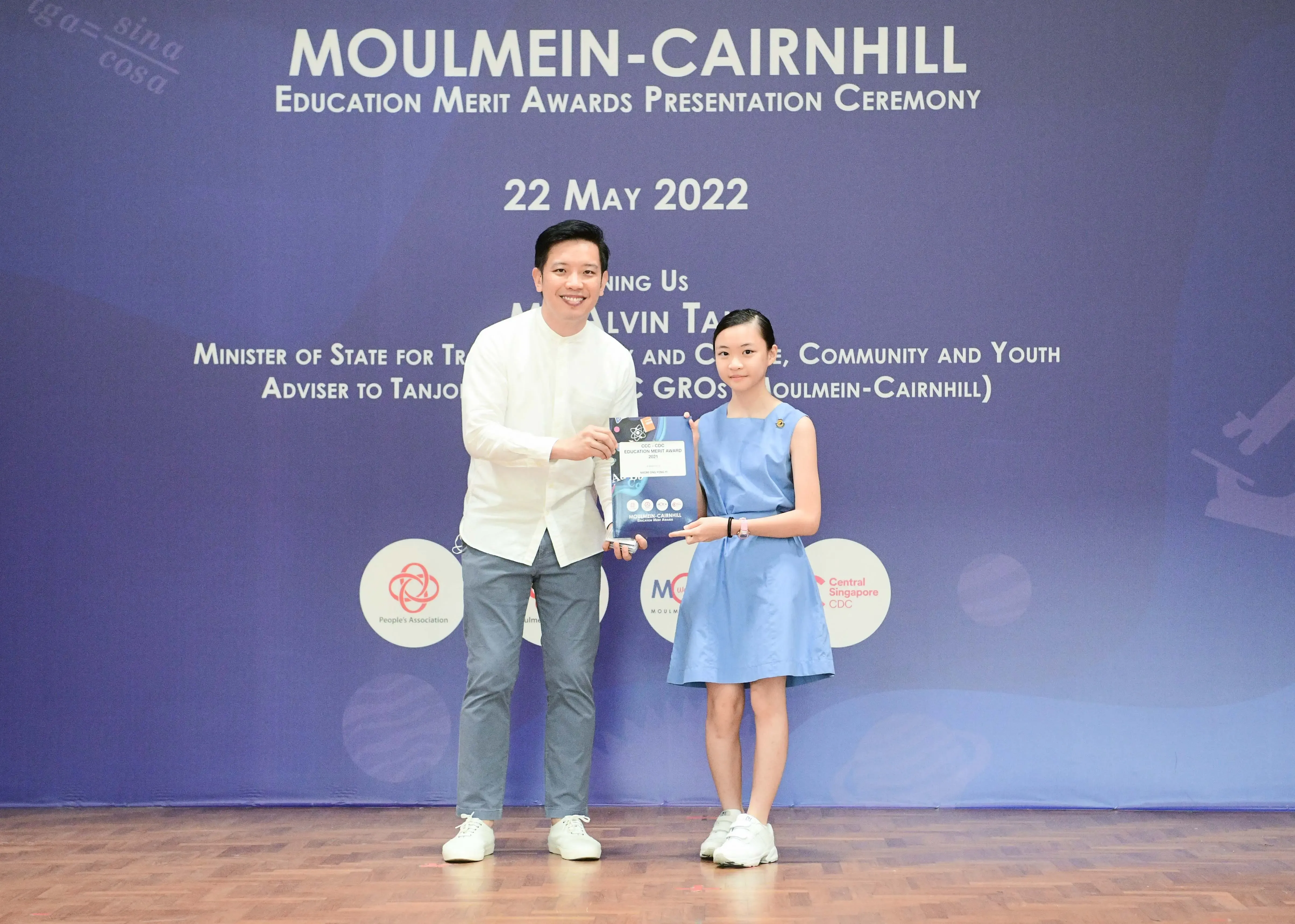 A man and a young girl hold an award certificate at the Moulmein-Cairnhill Education Merit Awards ceremony on 22 May 2022.