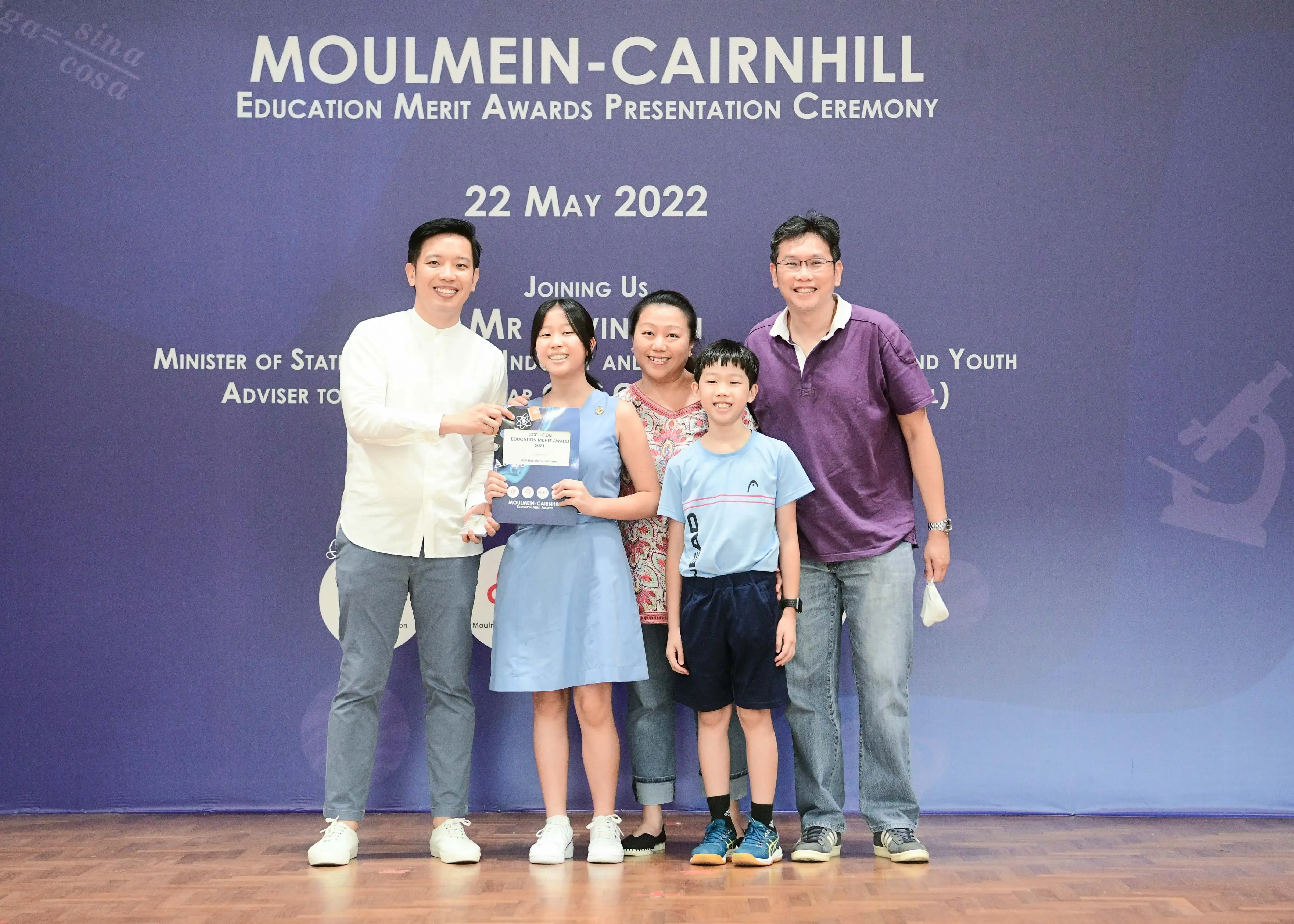 Five people pose on stage at the Moulmein-Cairnhill Education Merit Awards Presentation Ceremony on 22 May 2022.