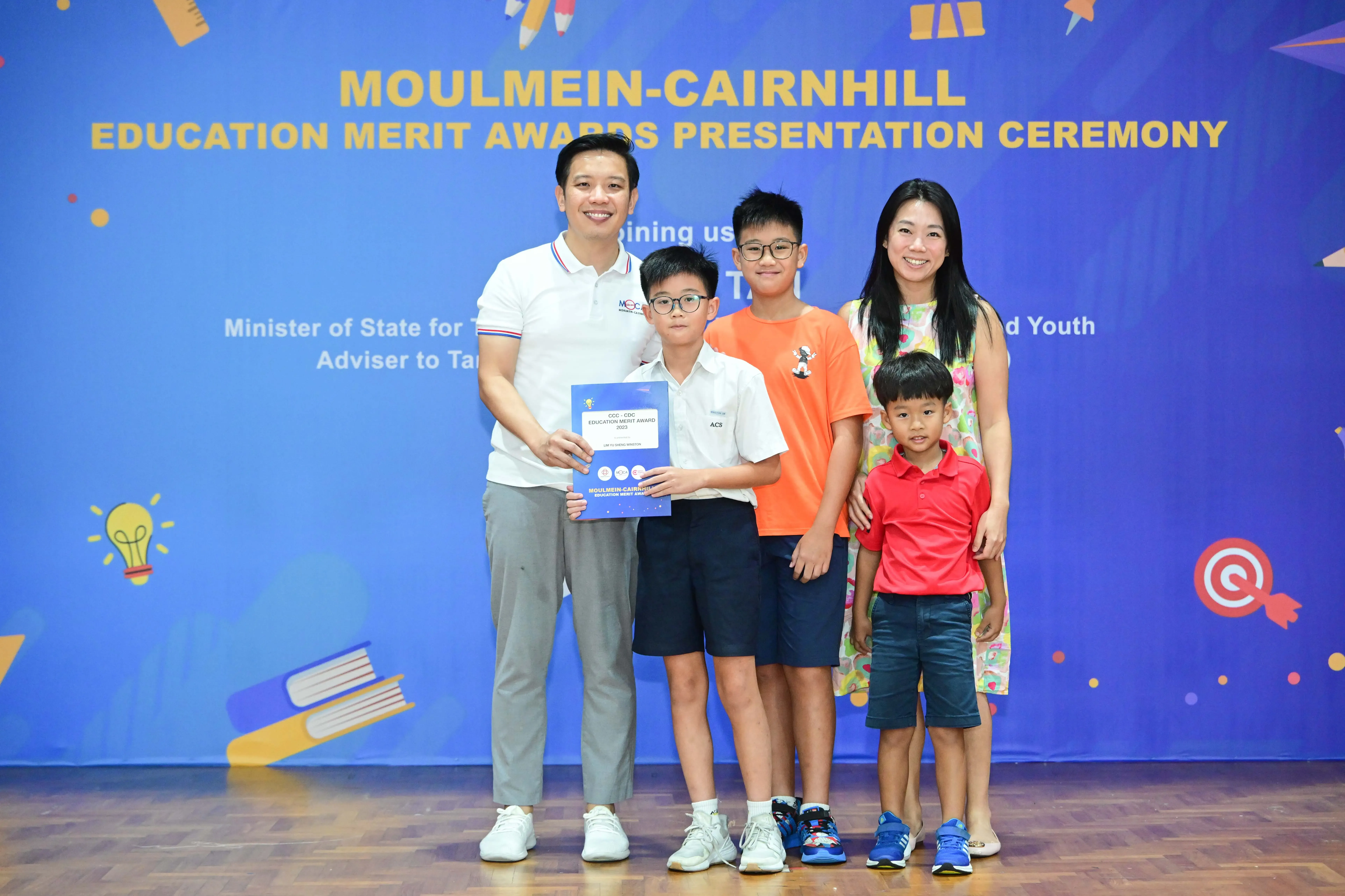 Two adults and three boys pose with a certificate at the Moulmein-Cairnhill Education Merit Awards Presentation Ceremony.