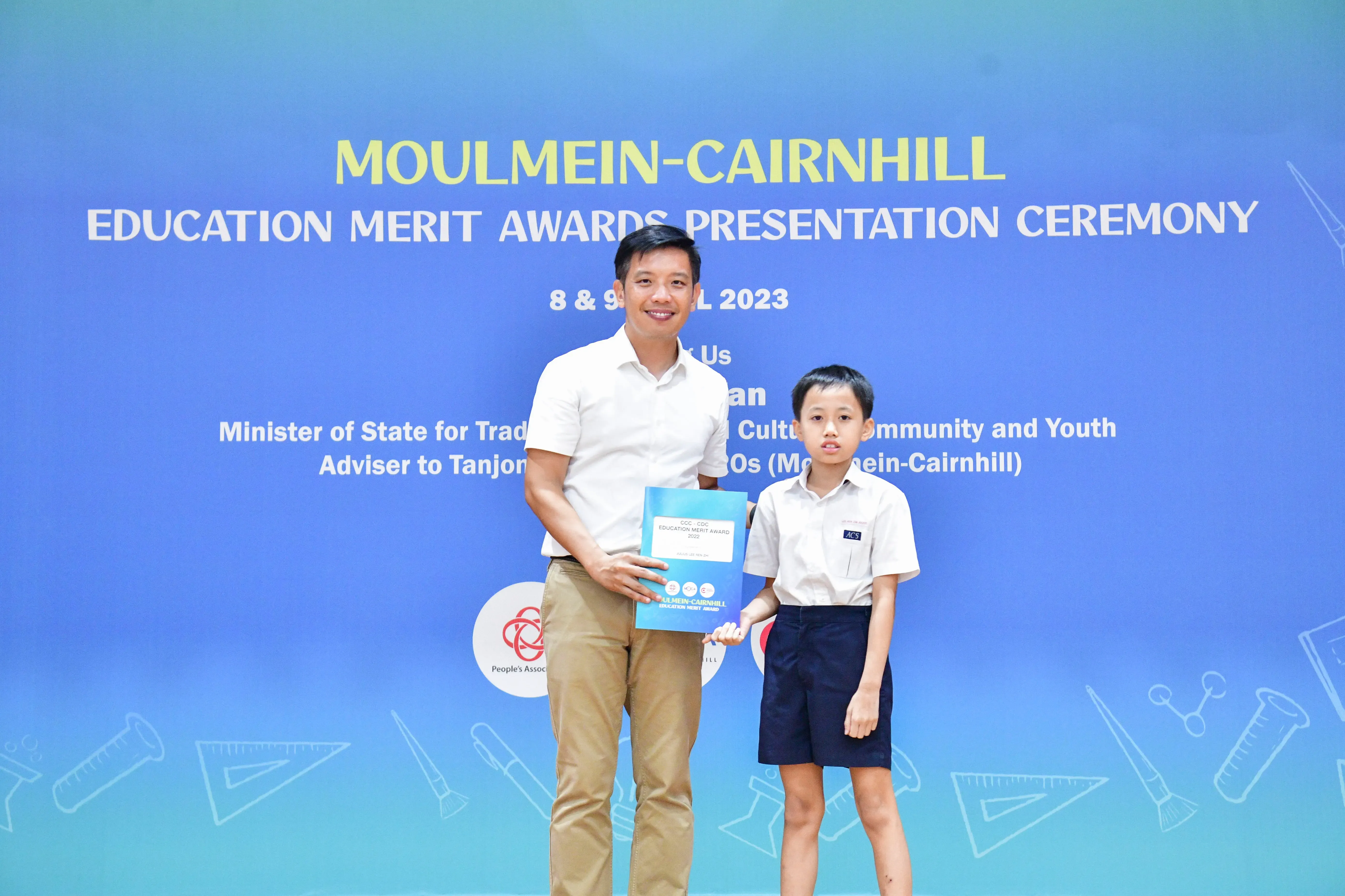 An adult and a young boy in school uniform pose with an award at the Moulmein-Cairnhill Education Merit Awards 2023.