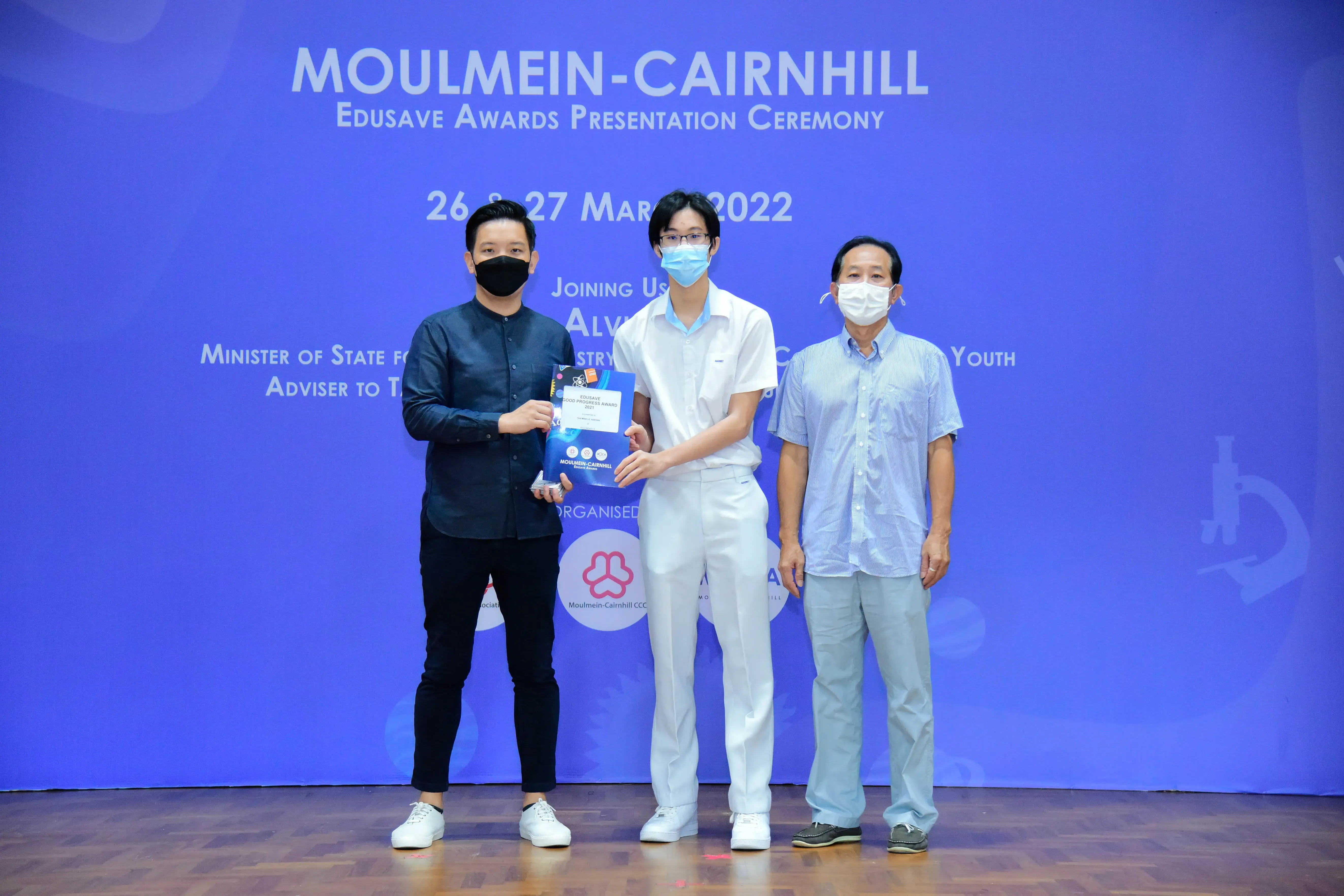 Three masked people stand together at the Moulmein-Cairnhill Edusave Awards Presentation Ceremony in March 2022.