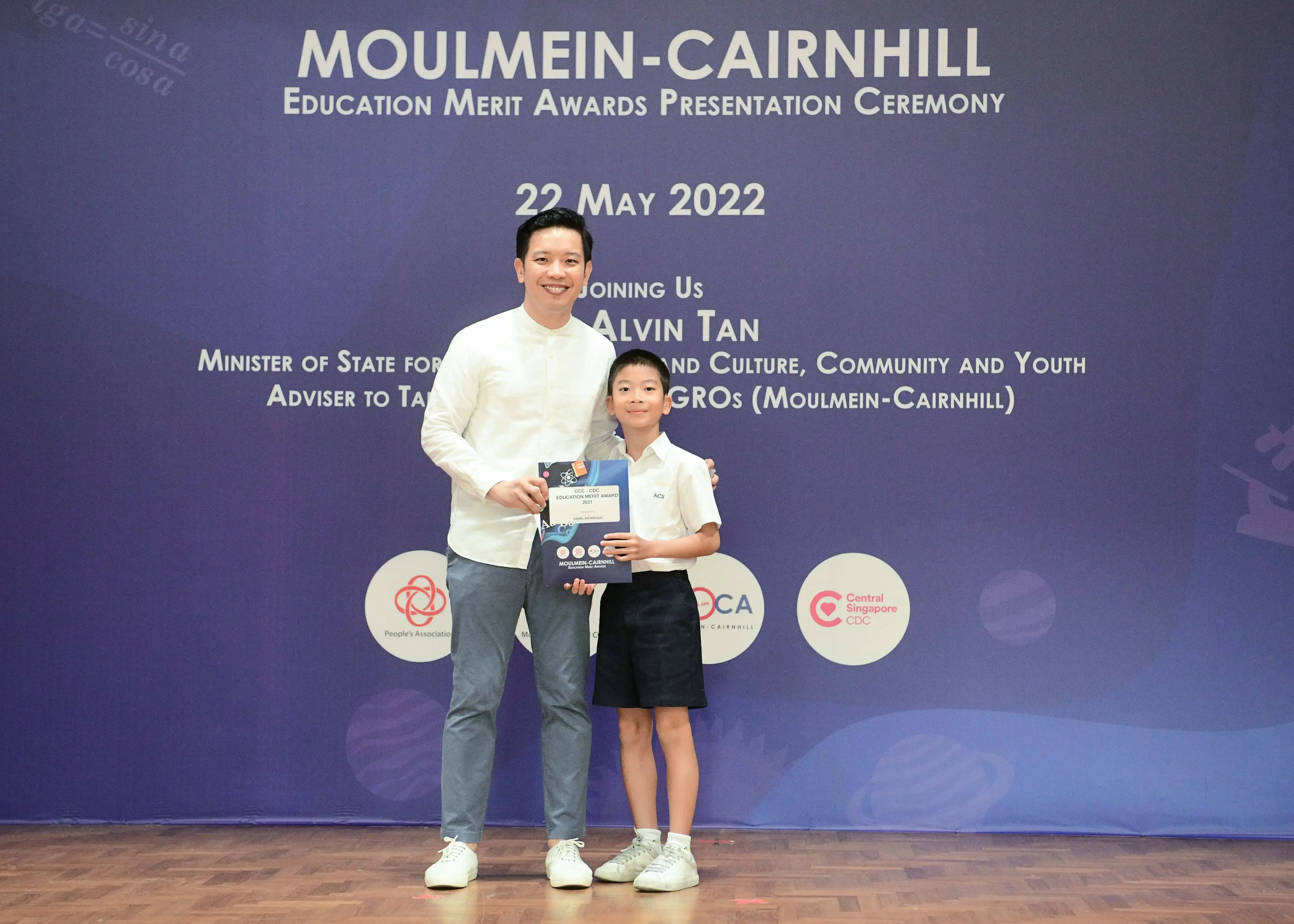 A man and a young boy pose holding a certificate at the Moulmein-Cairnhill Education Merit Awards on 22 May 2022.