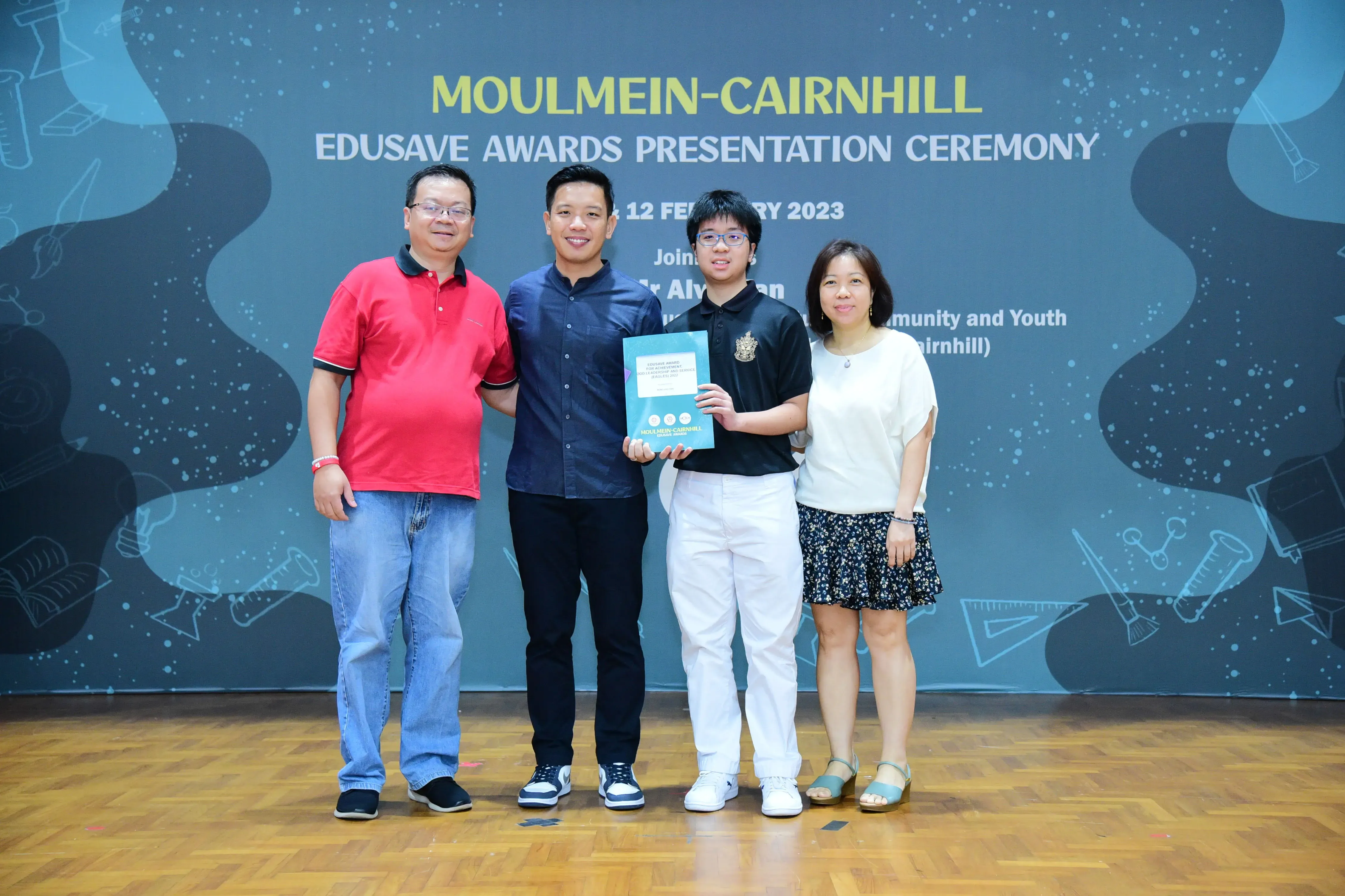 Four people pose smiling at the Moulmein-Cairnhill Edusave Awards Presentation Ceremony on 12 February 2023.