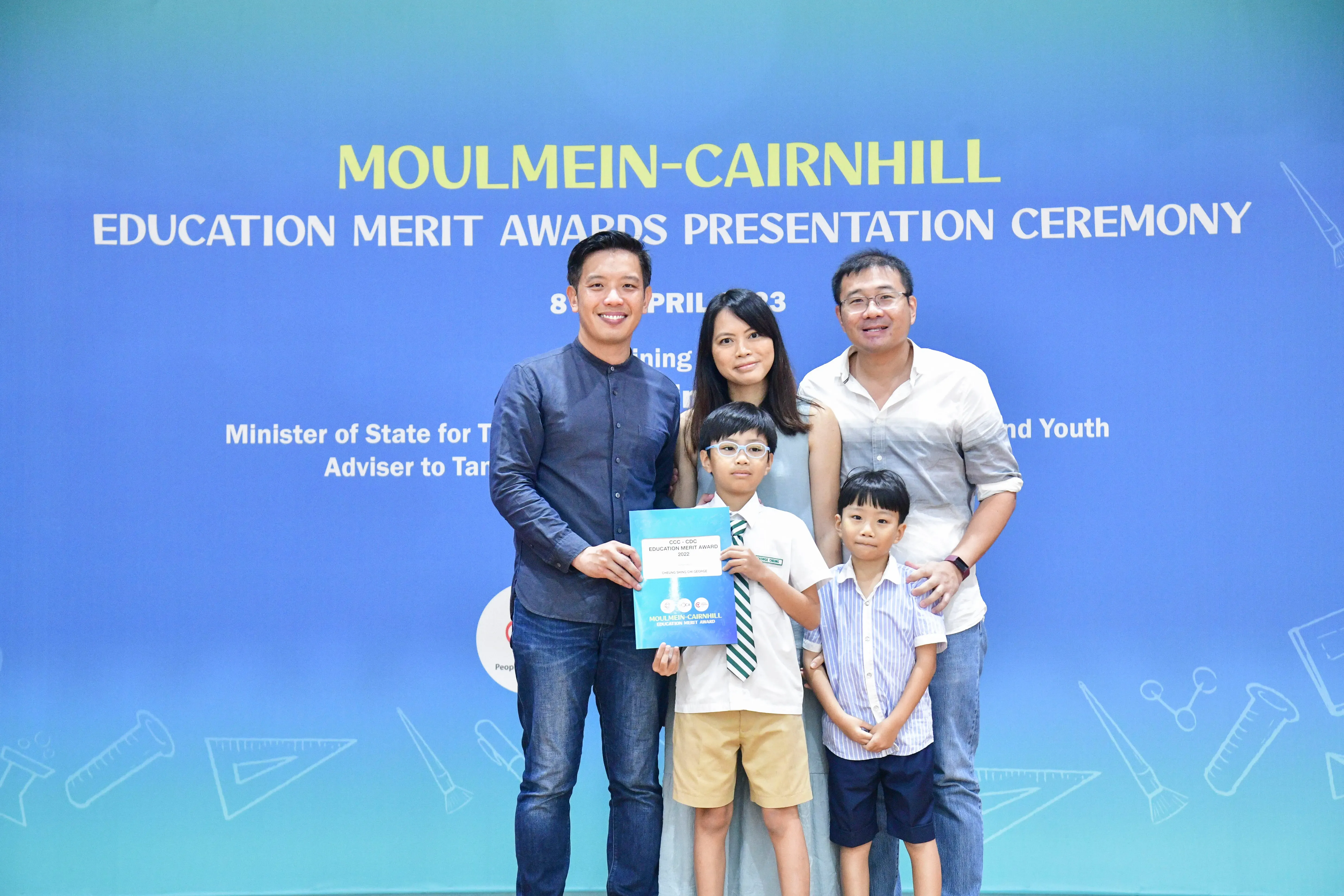Family of five posing at Moulmein-Cairnhill Education Merit Awards Presentation Ceremony, boy holding award certificate.