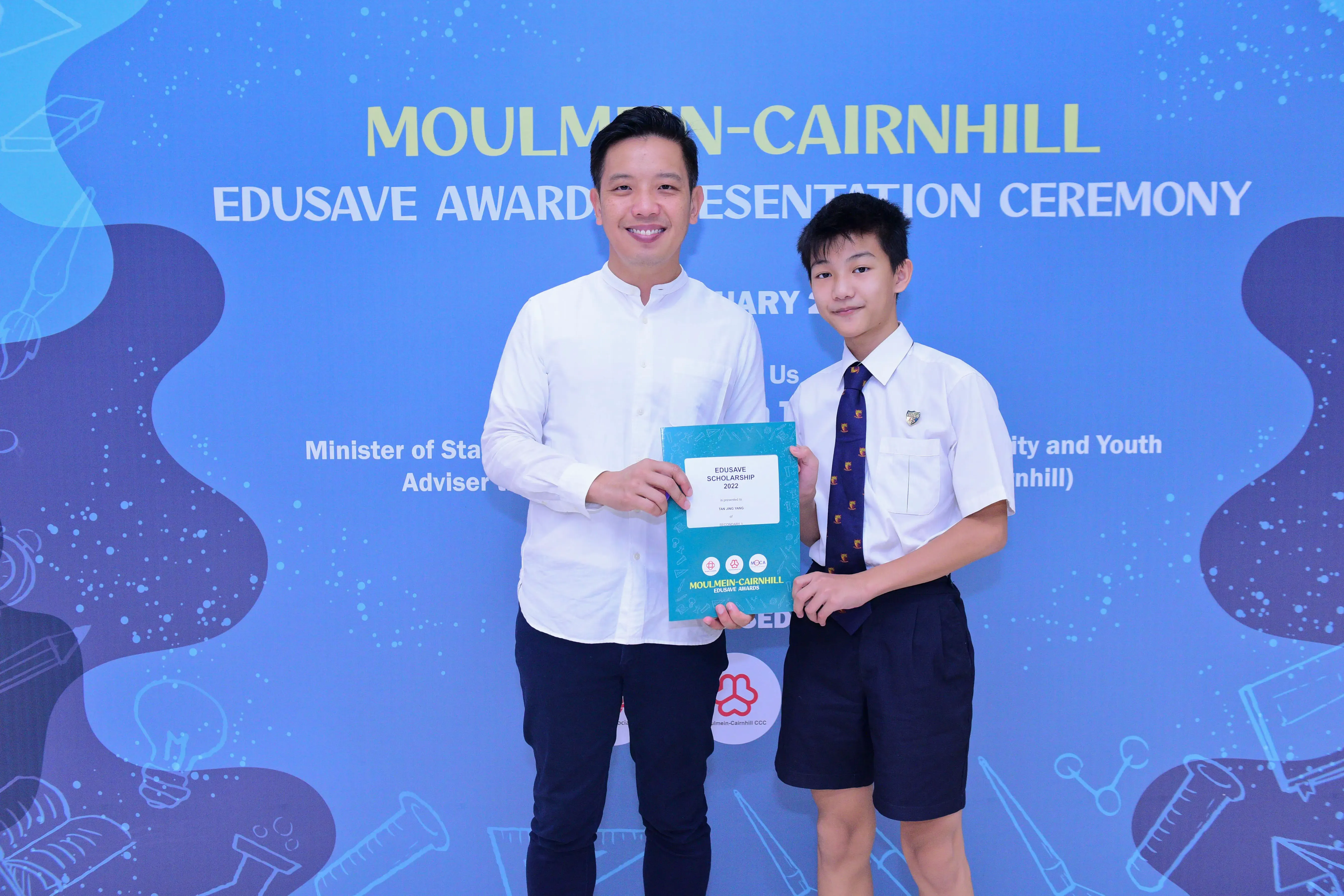 Two people hold an Edusave Scholarship certificate at the Moulmein-Cairnhill Edusave Awards Presentation Ceremony.
