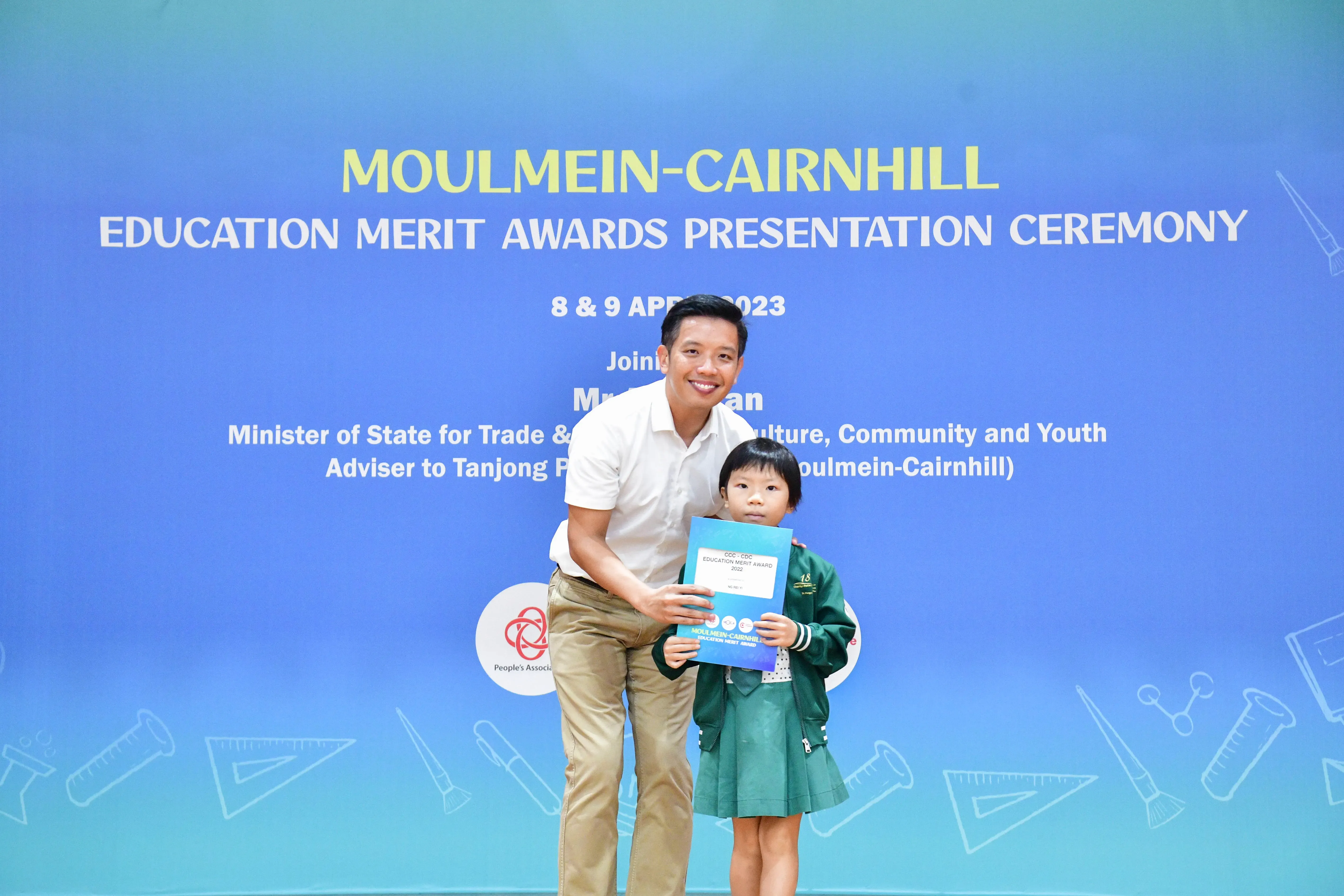 A man and a young girl hold a certificate together at the Moulmein-Cairnhill Education Merit Awards Ceremony in 2023.