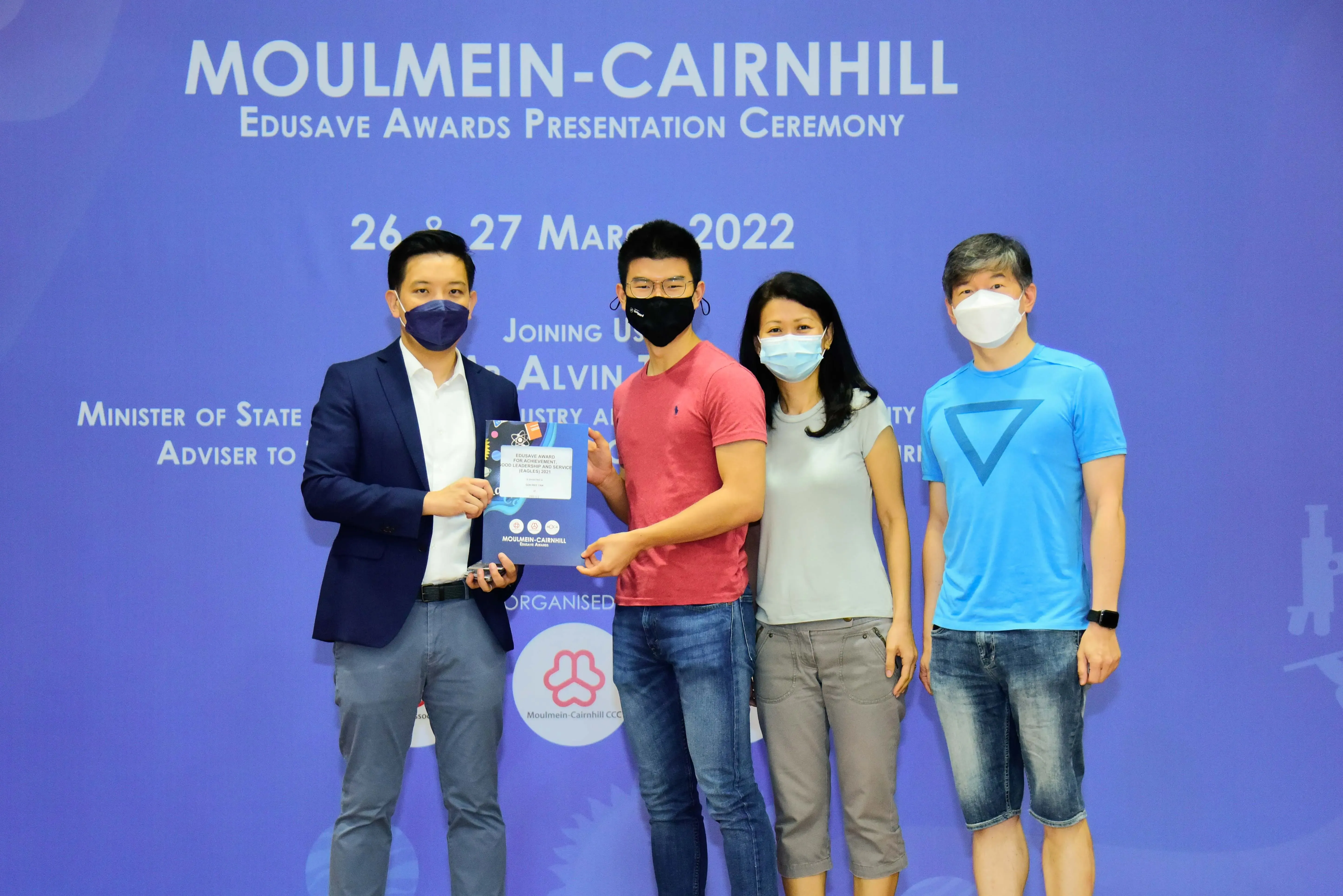 Four masked people pose at the Moulmein-Cairnhill Edusave Awards Presentation Ceremony on 26-27 March 2022.