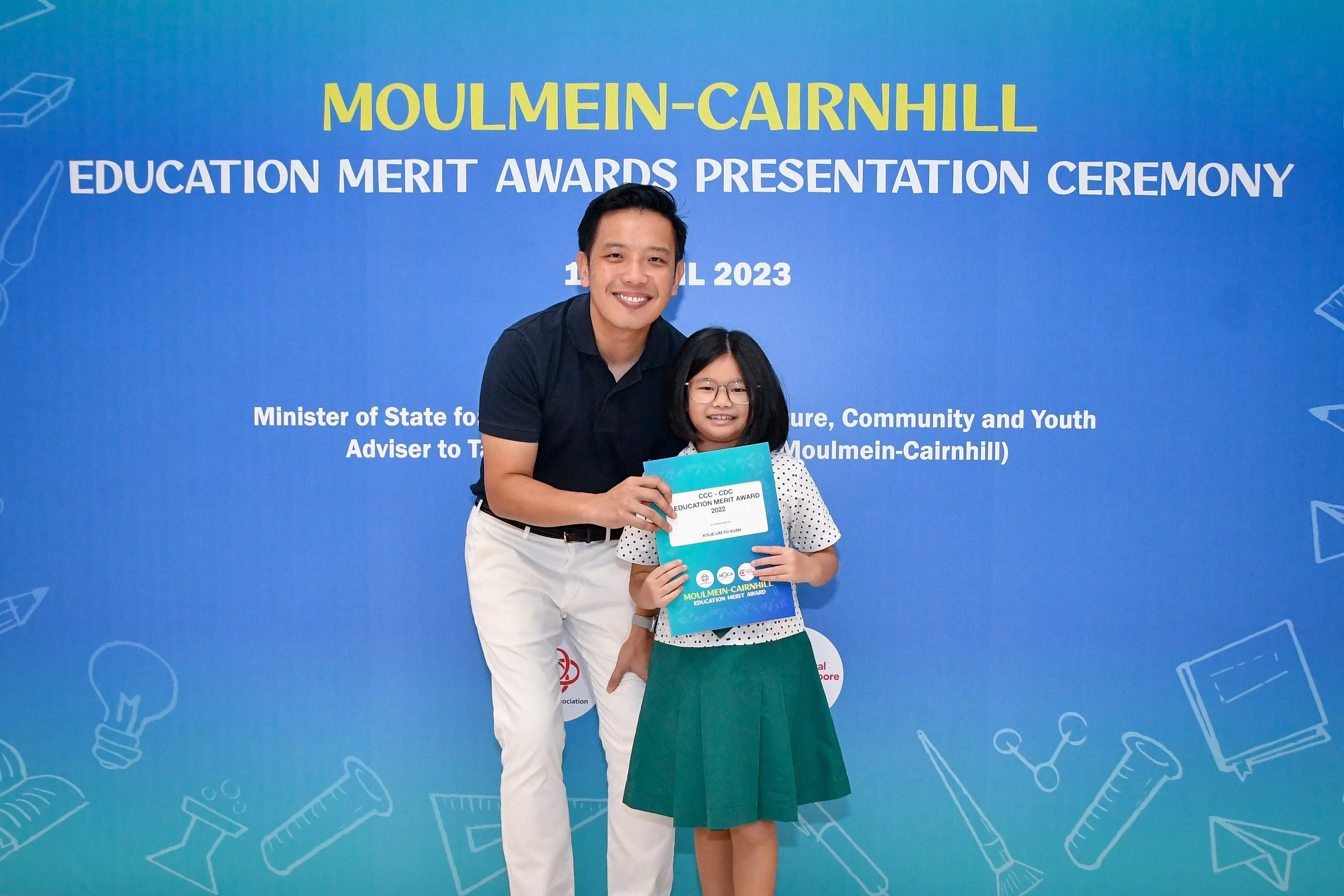 Man and young girl holding an award certificate at the Moulmein-Cairnhill Education Merit Awards Ceremony 2023.