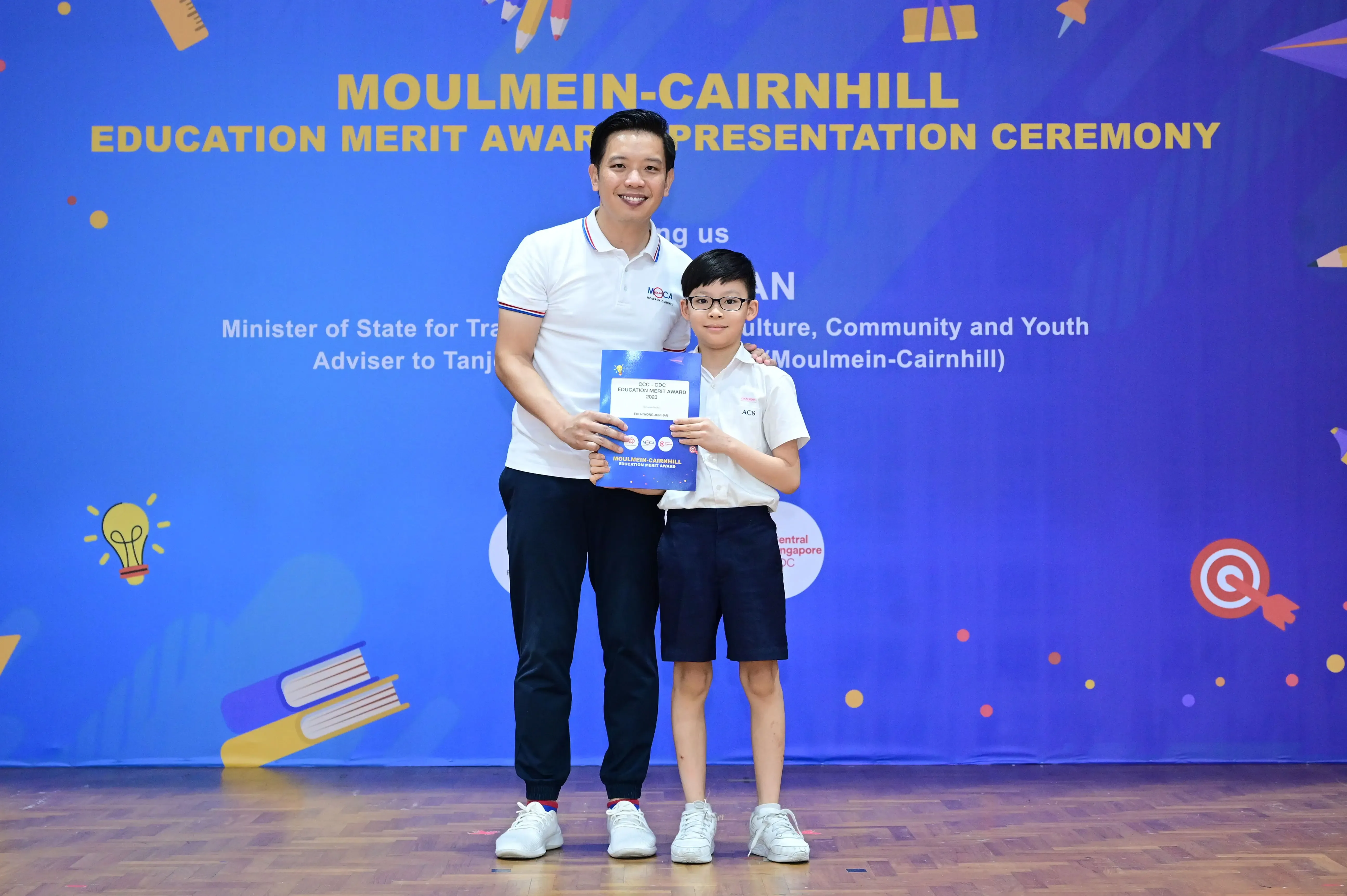 Man and young boy holding an award certificate at the Moulmein-Cairnhill Education Merit Award Presentation Ceremony.