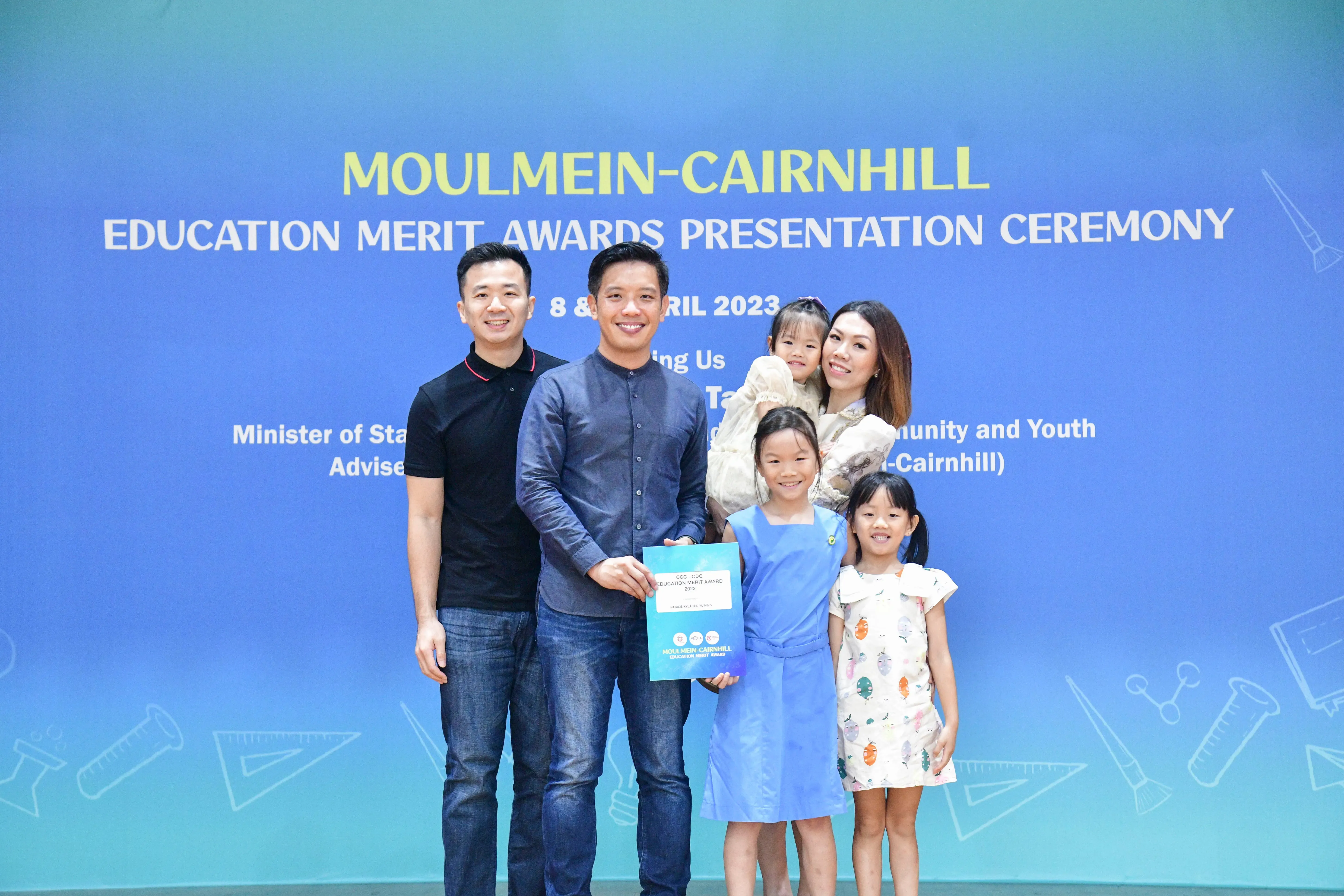 A family poses with an award at the Moulmein-Cairnhill Education Merit Awards Presentation Ceremony in April 2023.